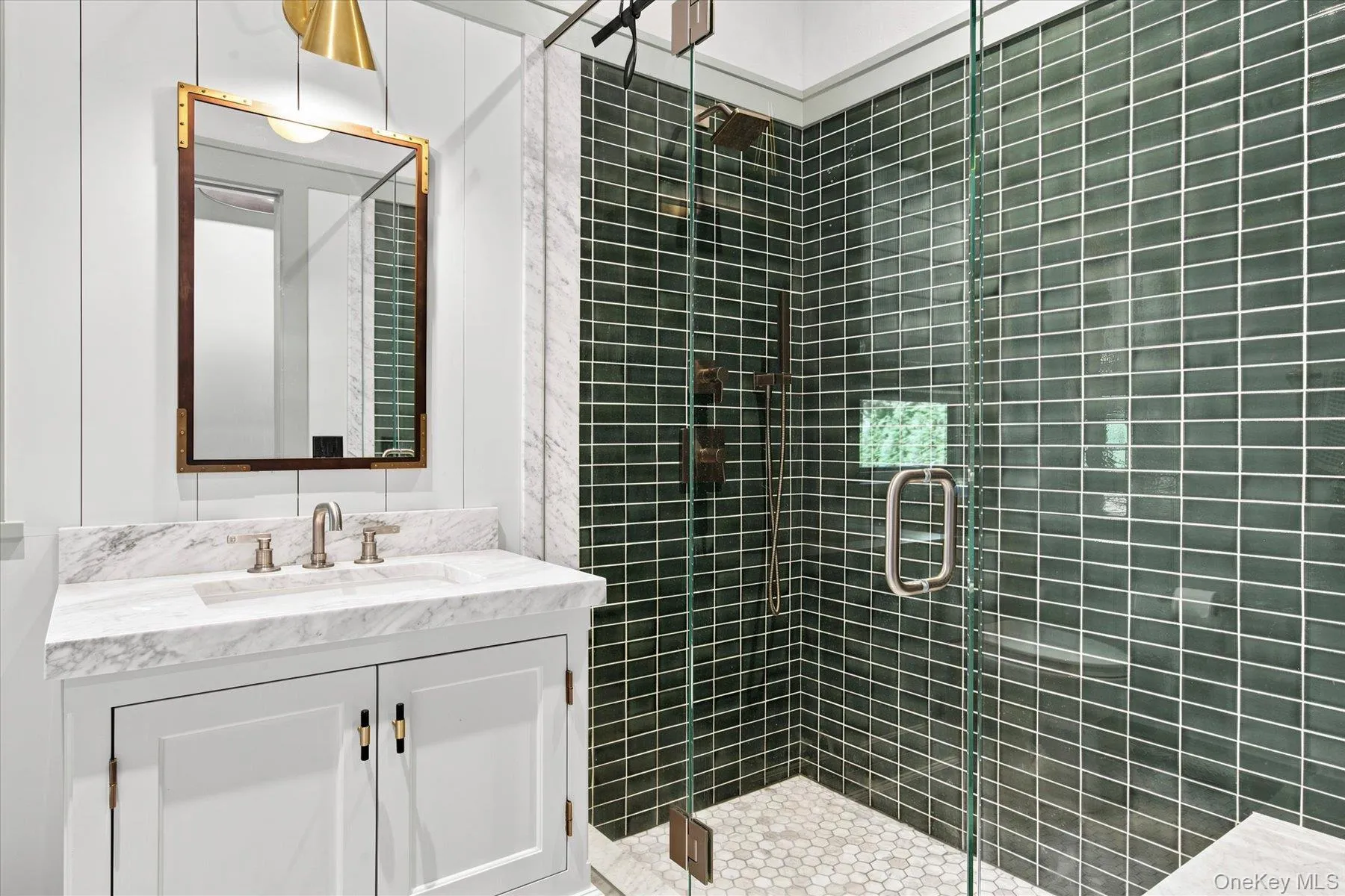 Glass-enclosed shower with dark green subway tile surround and hexagonal floor tile Glass-enclosed shower with dark green subway tile surround and hexagonal floor tile