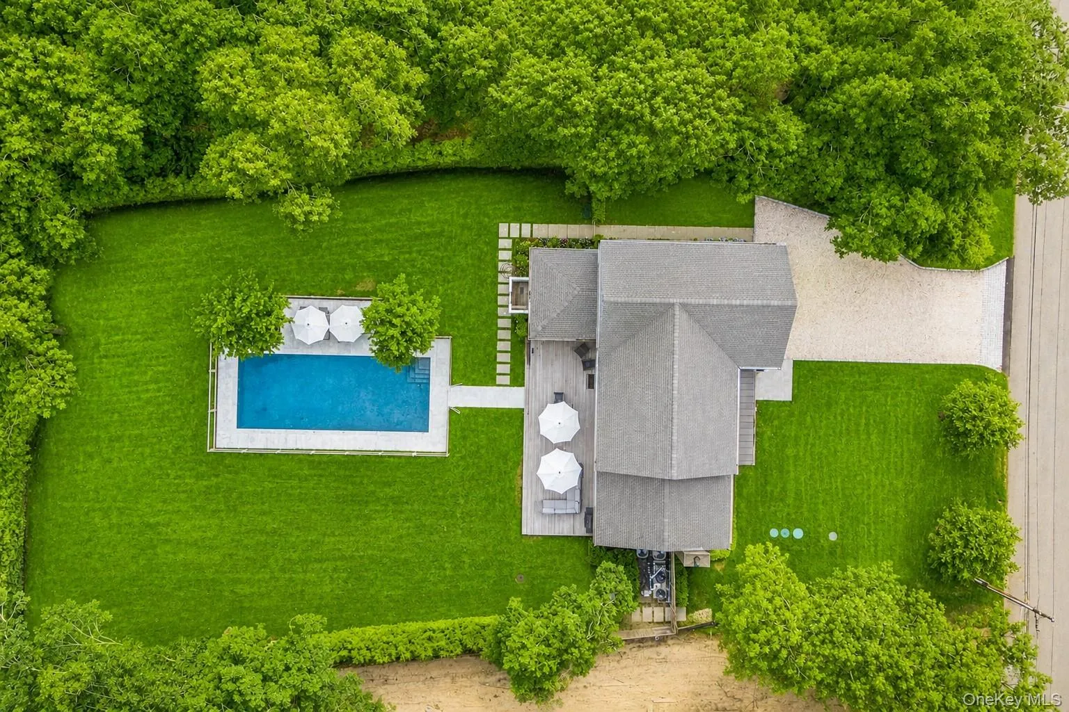 Expansive green lawn surrounds a rectangular swimming pool with integrated steps, featuring a stone surround Expansive green lawn surrounds a rectangular swimming pool with integrated steps, featuring a stone surround