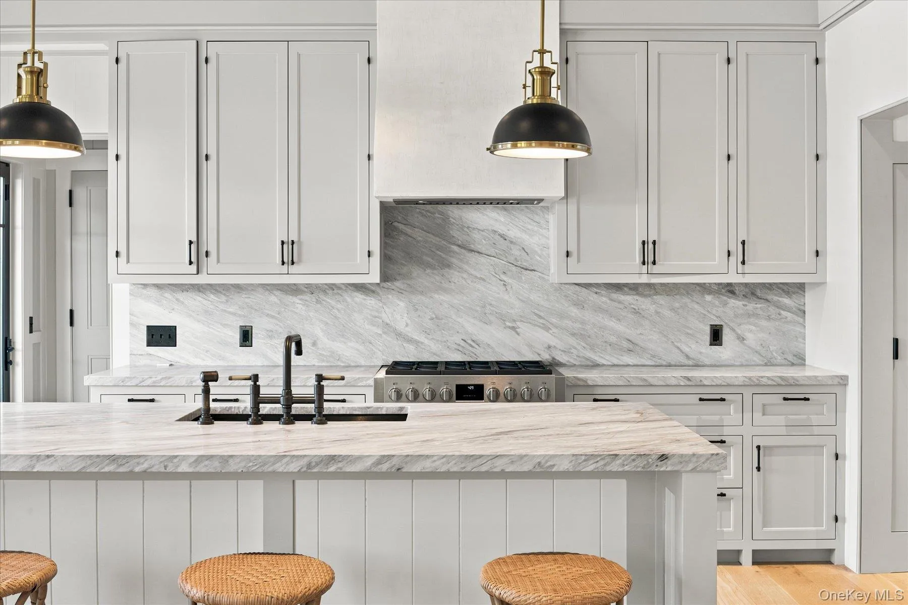 Kitchen featuring white shaker-style cabinetry, a built-in range hood, and a gas range Kitchen featuring white shaker-style cabinetry, a built-in range hood, and a gas range