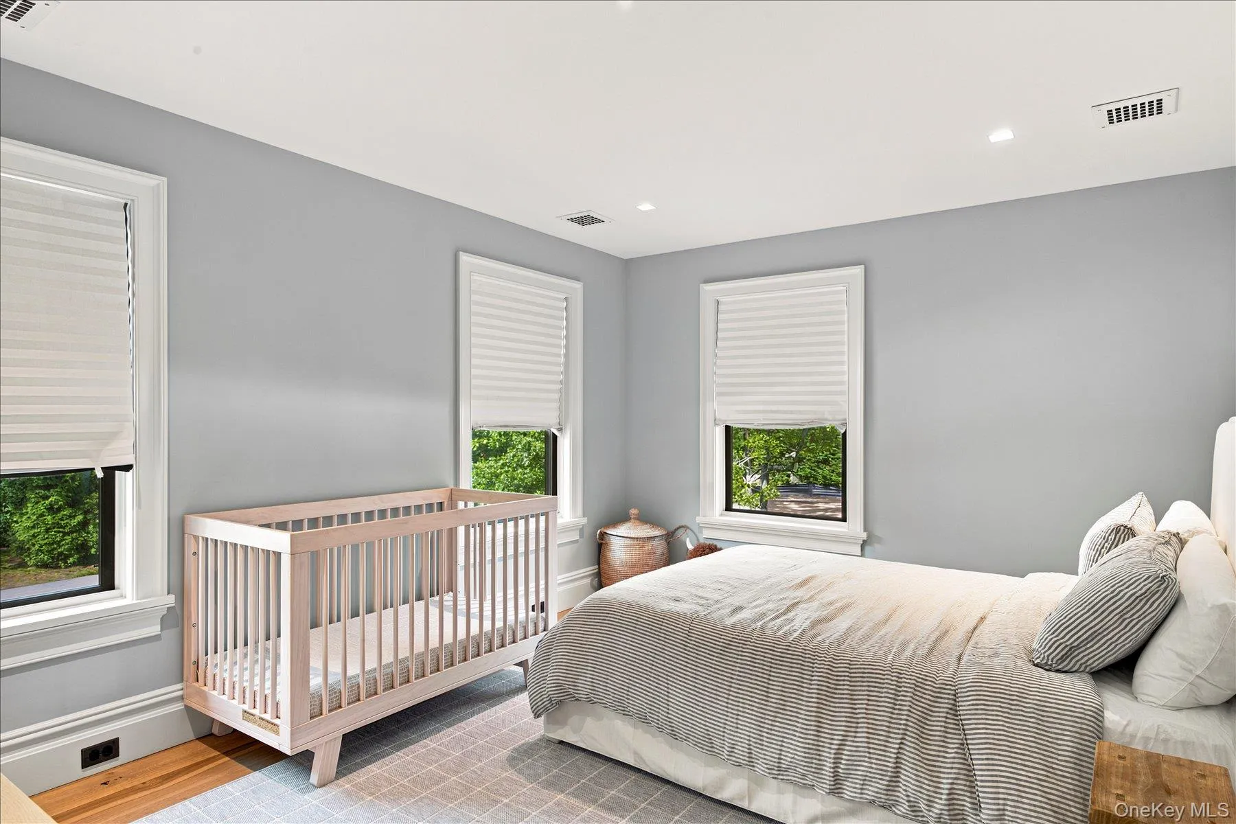 Bright room featuring two windows with white cellular shades, light gray wall paint, recessed lighting, and wood-finish flooring Bright room featuring two windows with white cellular shades, light gray wall paint, recessed lighting, and wood-finish flooring