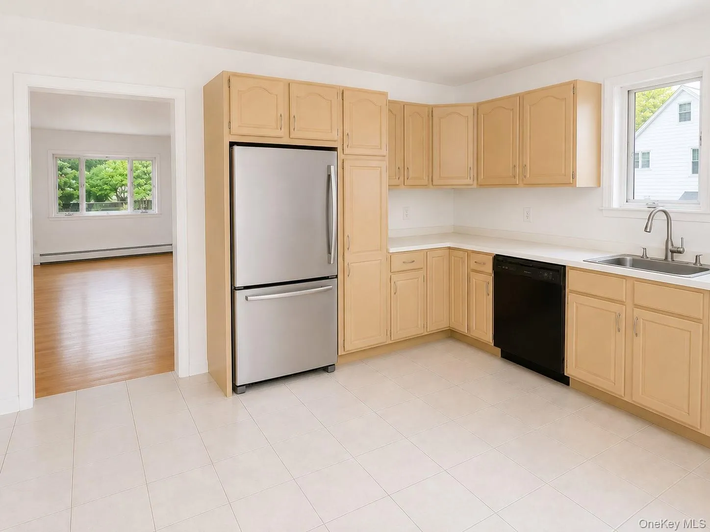 Kitchen featuring light wood-finish cabinetry, white countertops, and a stainless steel refrigerator Kitchen featuring light wood-finish cabinetry, white countertops, and a stainless steel refrigerator