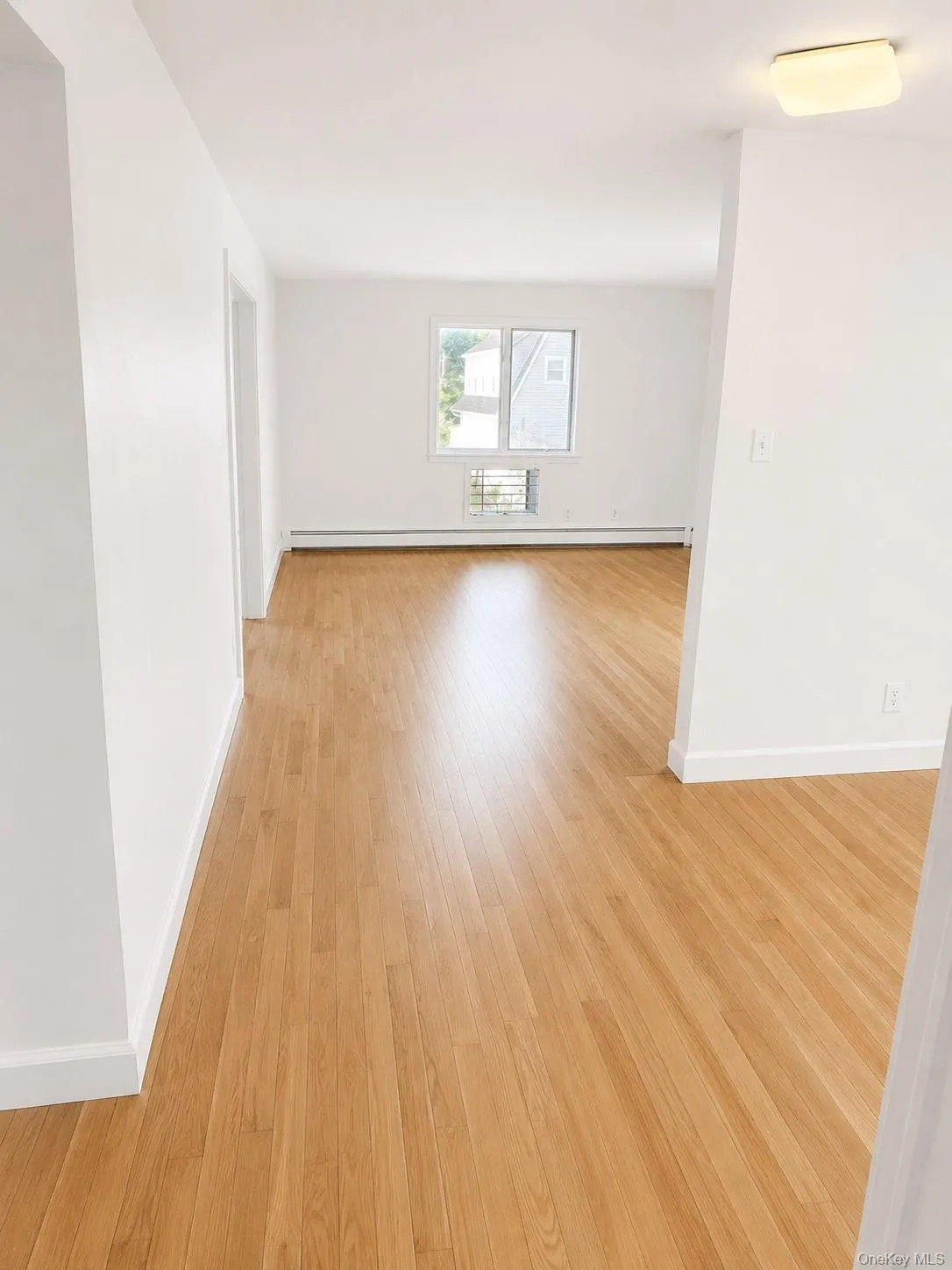 Bright interior Dining Area and Hall featuring wood-finish flooring, white walls, and white trim Bright interior Dining Area and Hall featuring wood-finish flooring, white walls, and white trim