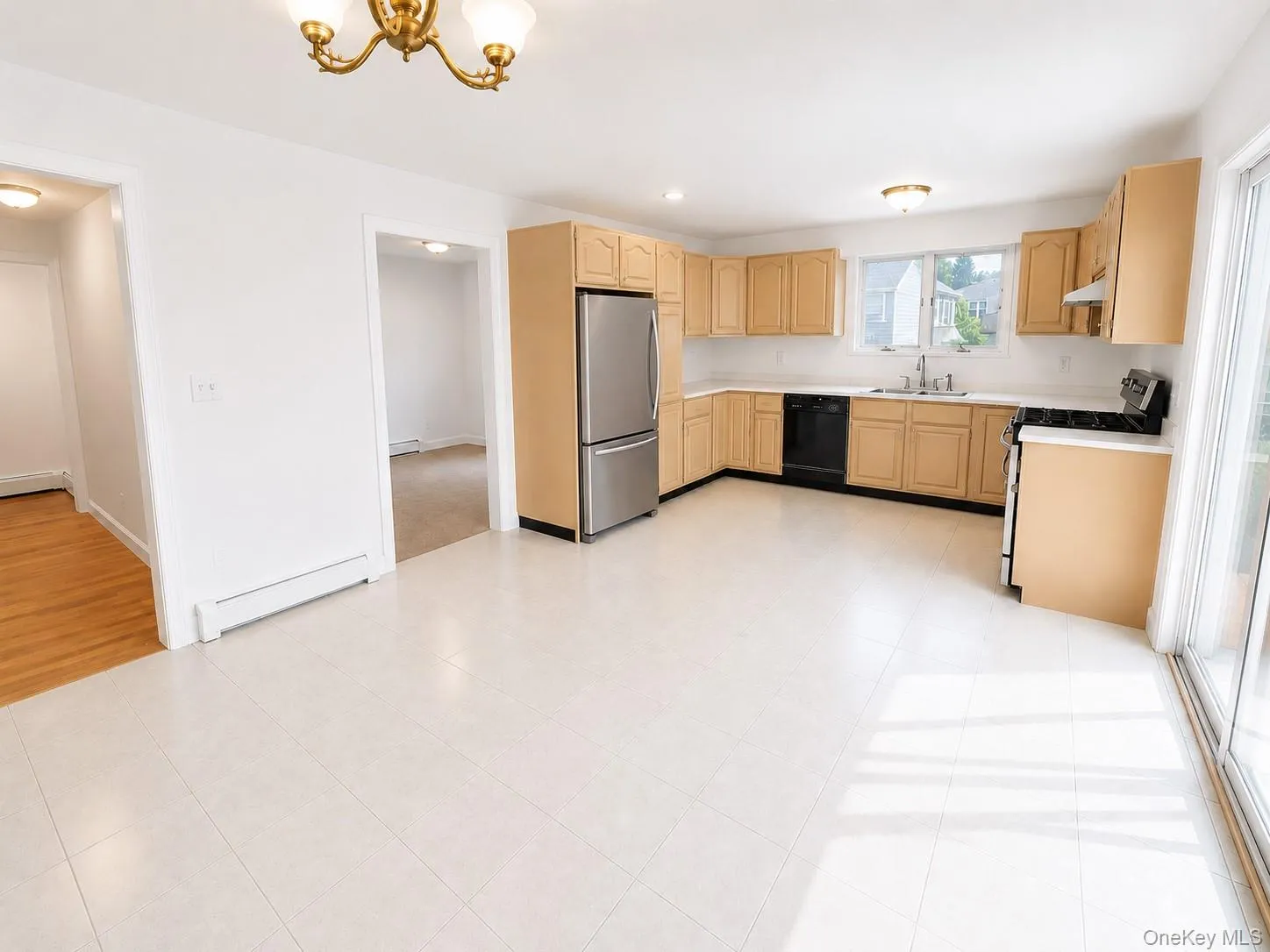 Kitchen featuring light wood-finish cabinetry, stainless steel refrigerator, black dishwasher, and a white tile backsplash Kitchen featuring light wood-finish cabinetry, stainless steel refrigerator, black dishwasher, and a white tile backsplash
