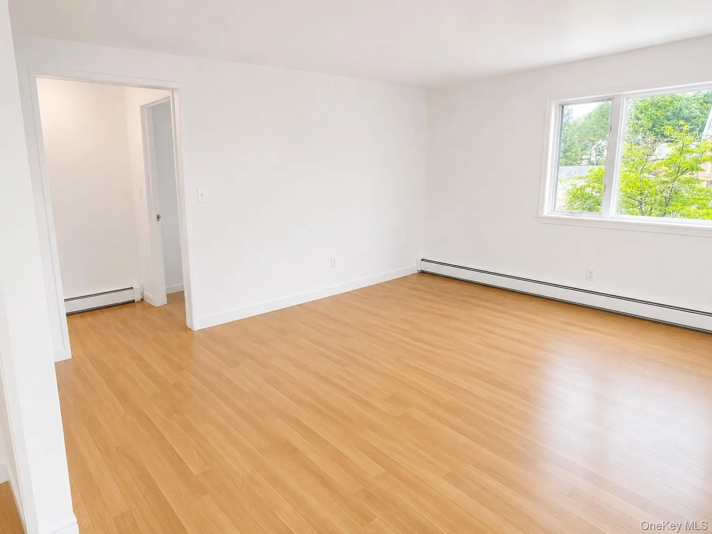 Spacious Living room featuring wood-finish flooring, crisp white walls, and multiple windows Spacious Living room featuring wood-finish flooring, crisp white walls, and multiple windows
