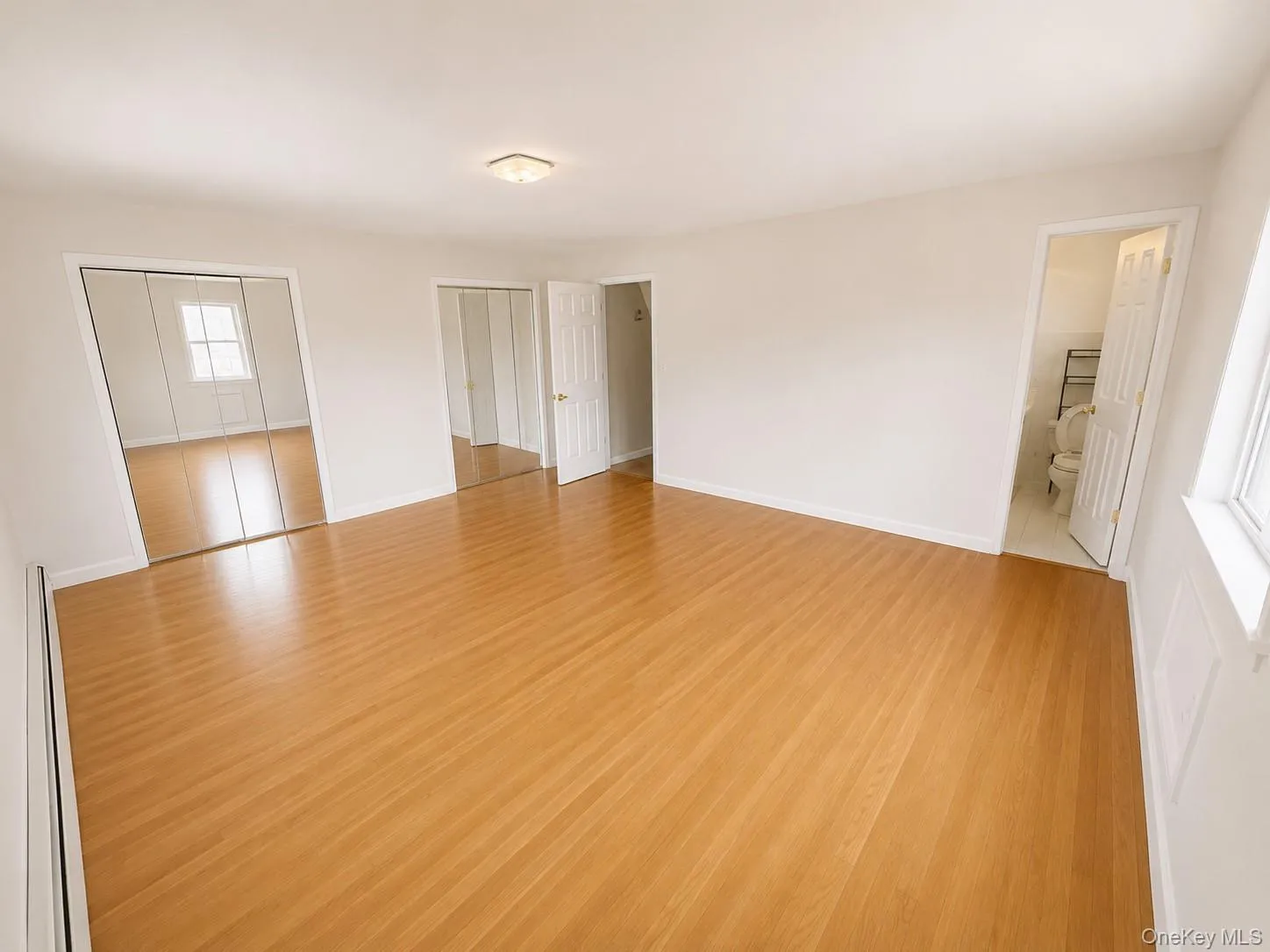 Spacious interior featuring wood-finish flooring, white walls, and a ceiling-mounted light fixture d large his and hers closets Spacious interior featuring wood-finish flooring, white walls, and a ceiling-mounted light fixture d large his and hers closets