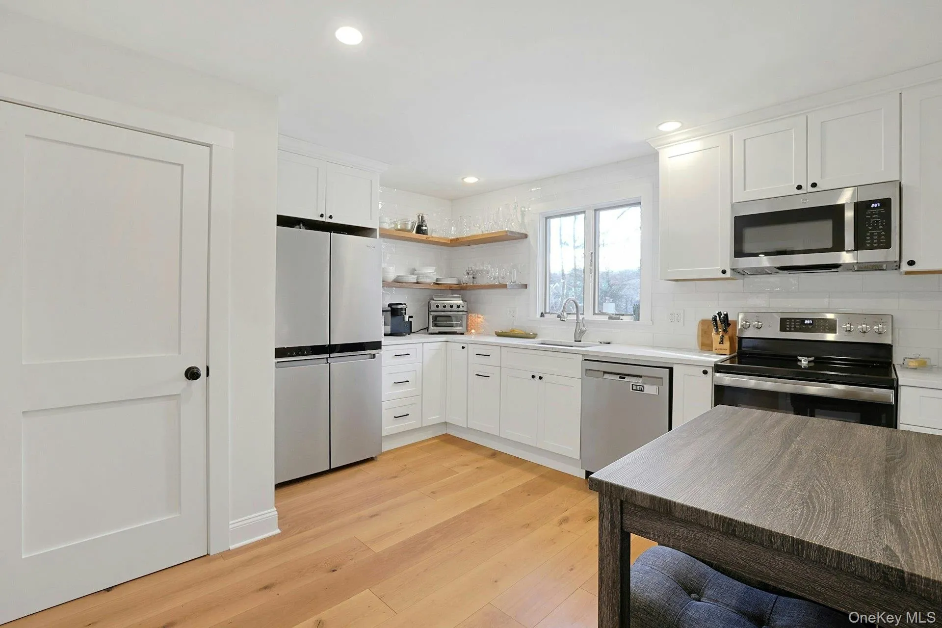 Kitchen featuring stainless steel appliances with open shelves, white cabinets, light countertops, and recessed lighting Kitchen featuring stainless steel appliances with open shelves, white cabinets, light countertops, and recessed lighting