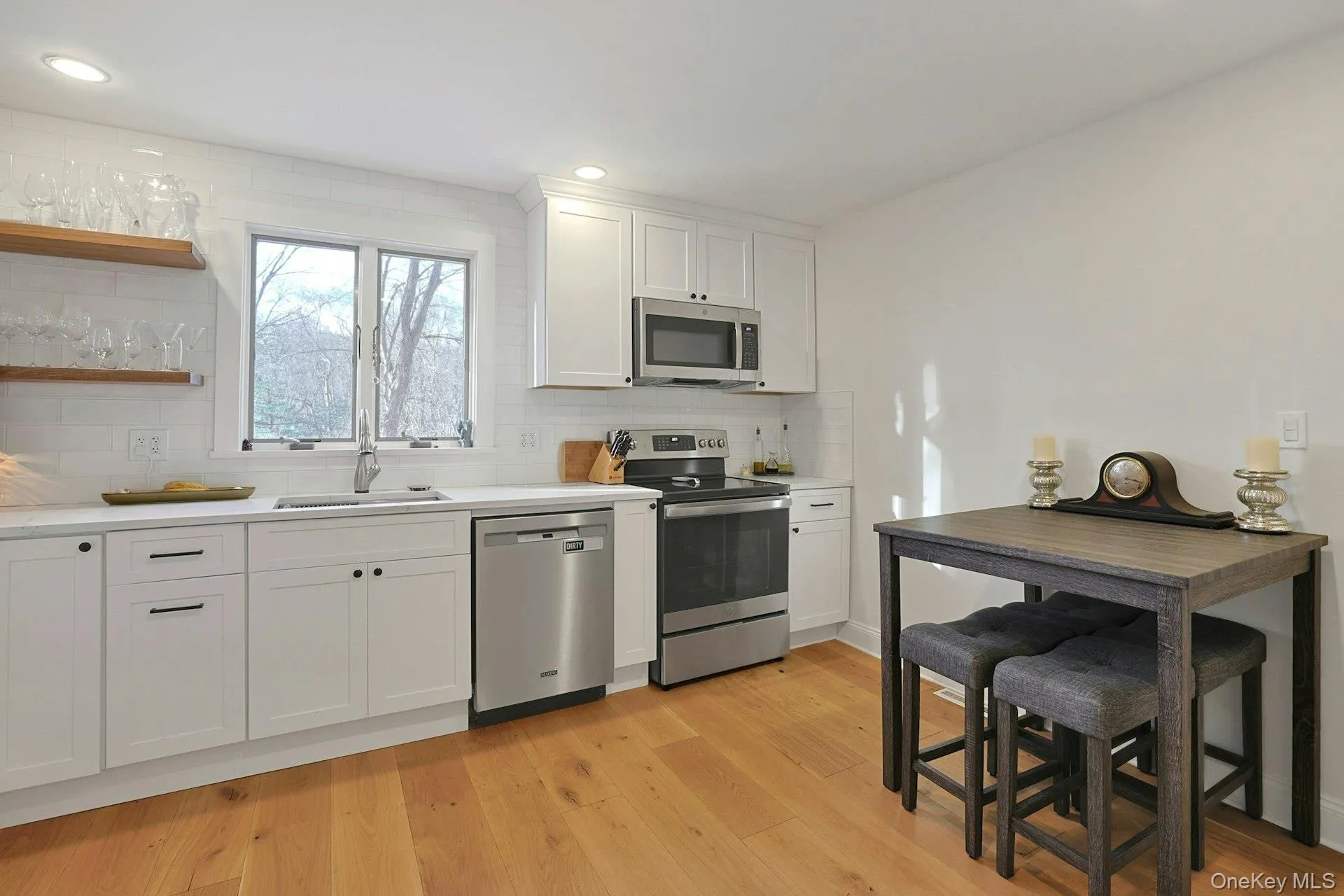 Kitchen featuring stainless steel appliances with open shelves, white cabinets, light countertops, recessed lighting, and decorative backsplash Kitchen featuring stainless steel appliances with open shelves, white cabinets, light countertops, recessed lighting, and decorative backsplash
