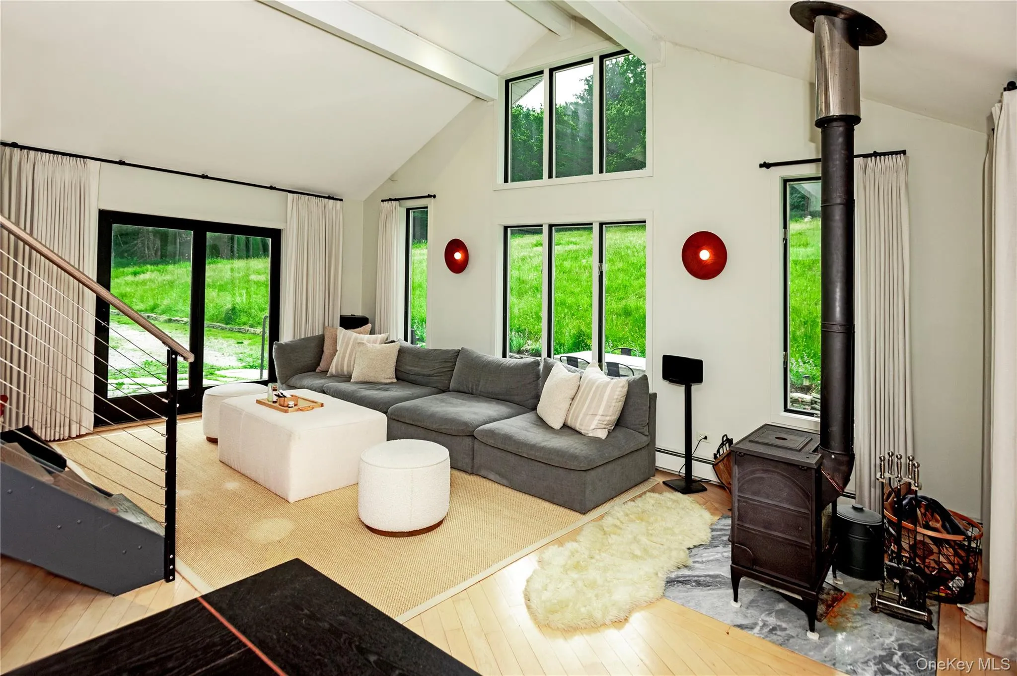 Main seating area and the wood stove in the vaulted great room with views of the grassy hill and mountain through the windows. Main seating area and the wood stove in the vaulted great room with views of the grassy hill and mountain through the windows.