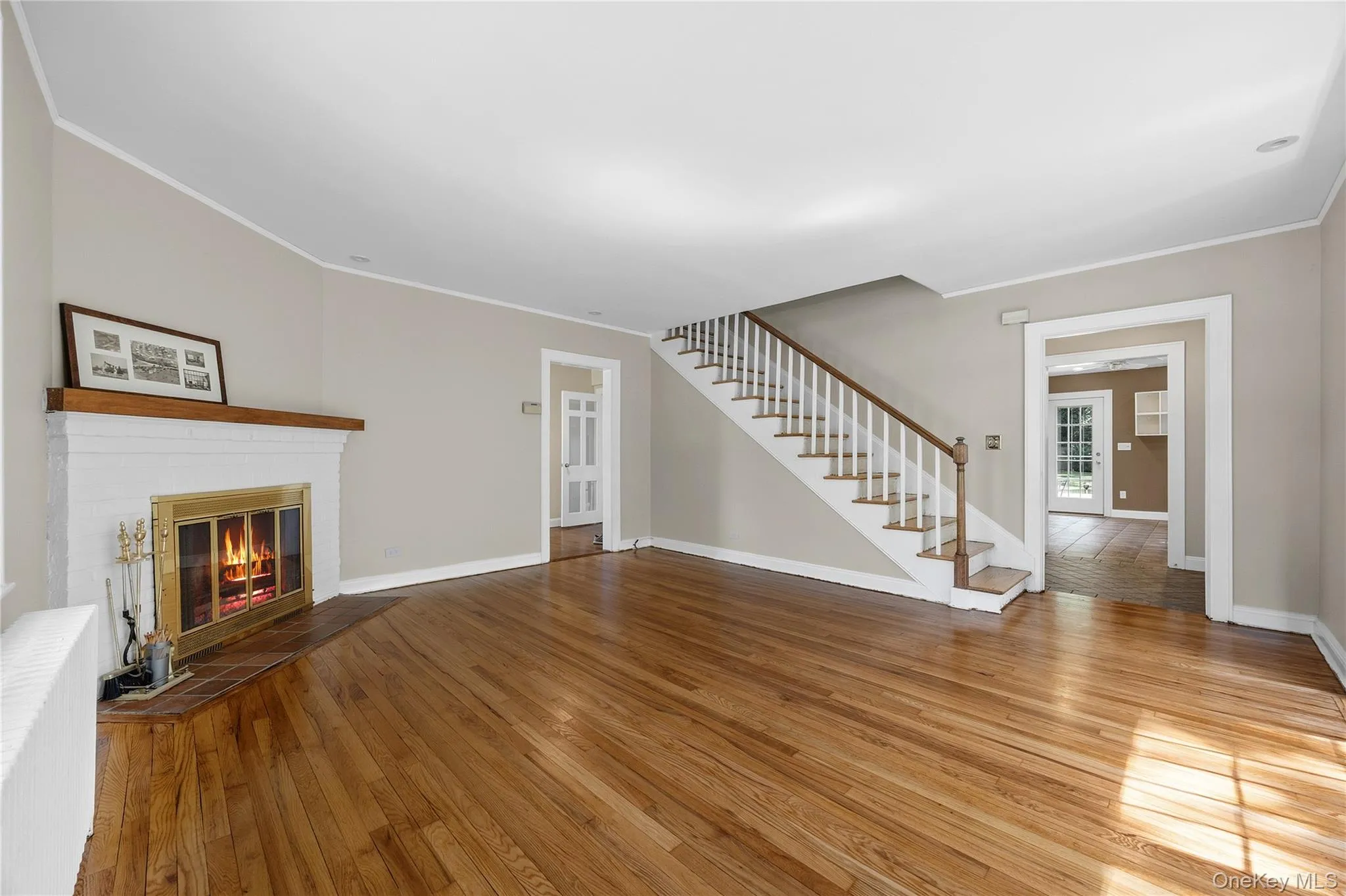 Gleaming Hardwood Floors in the living room with a view of the staircase to the second story and door to the left towards the kitchen. Gleaming Hardwood Floors in the living room with a view of the staircase to the second story and door to the left towards the kitchen.