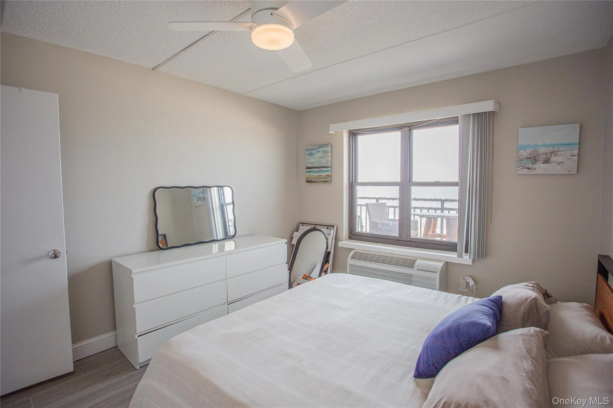 Bedroom featuring a textured ceiling, wood finished floors, ceiling fan, and an AC wall unit Bedroom featuring a textured ceiling, wood finished floors, ceiling fan, and an AC wall unit