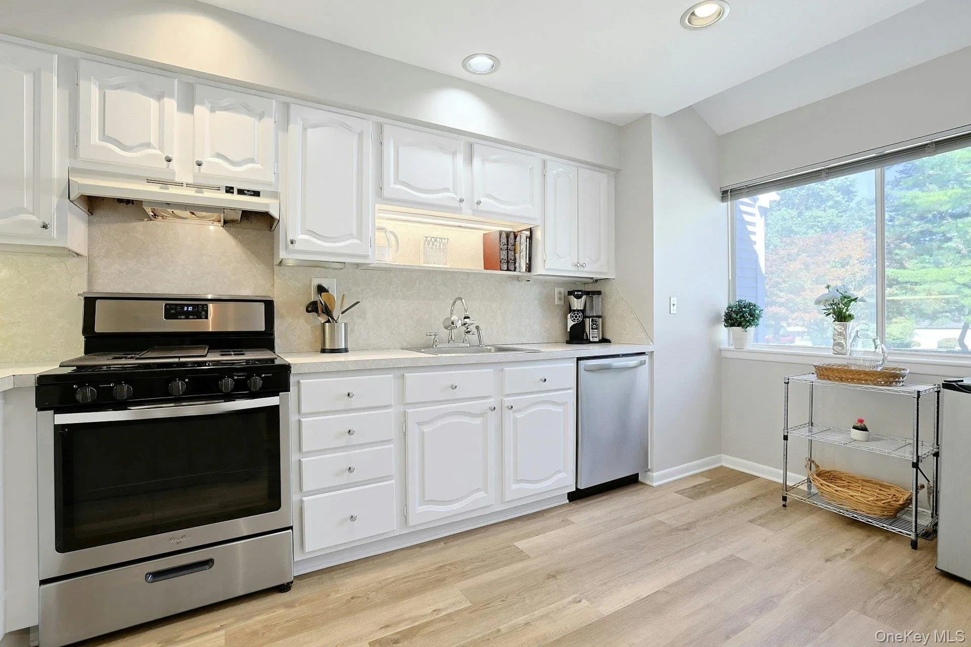 A bright, welcoming kitchen with hardwood floors and a large window for added natural light. A bright, welcoming kitchen with hardwood floors and a large window for added natural light.
