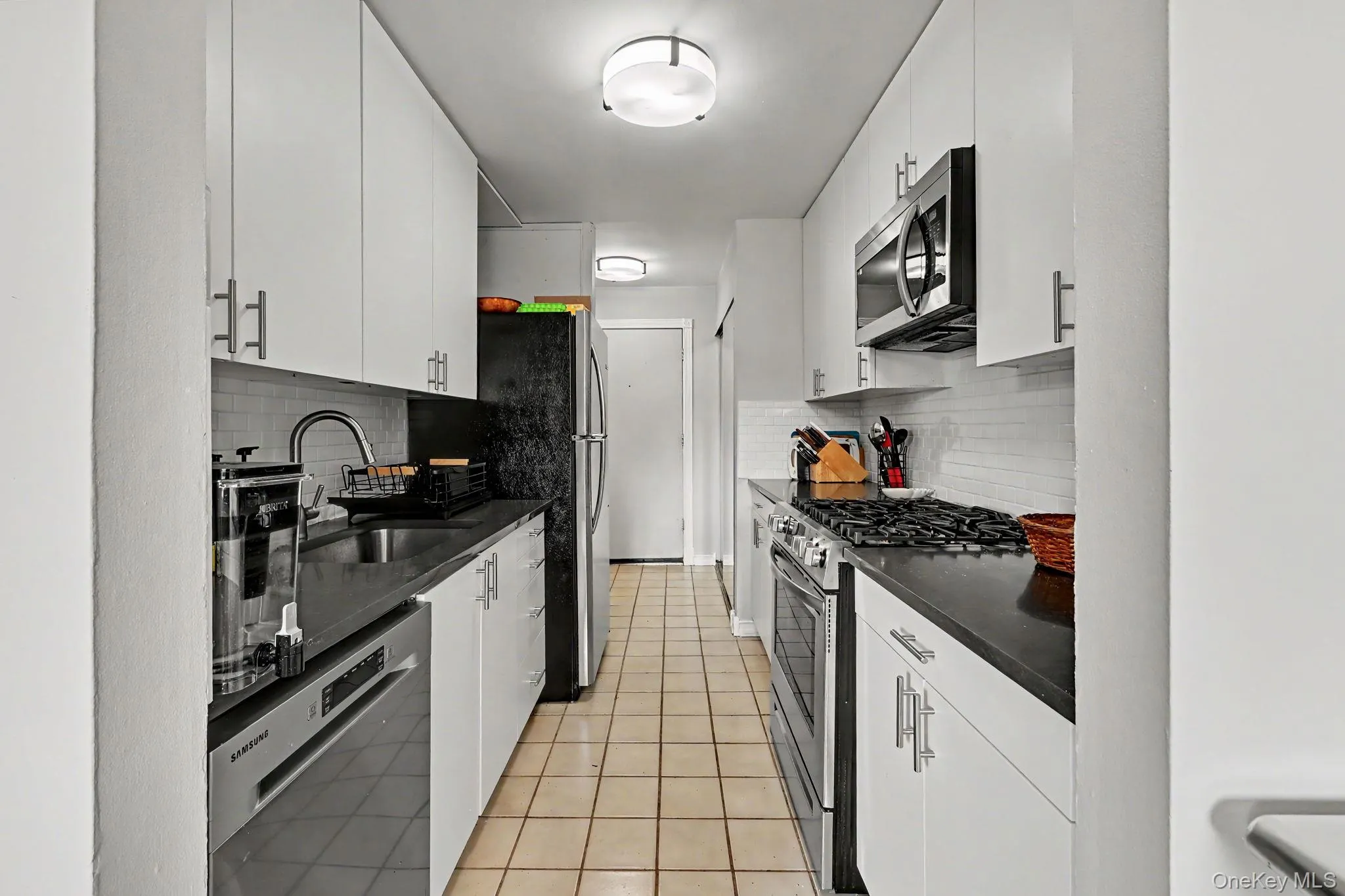 Galley kitchen with quartz countertops & stainless steel appliances. Galley kitchen with quartz countertops & stainless steel appliances.