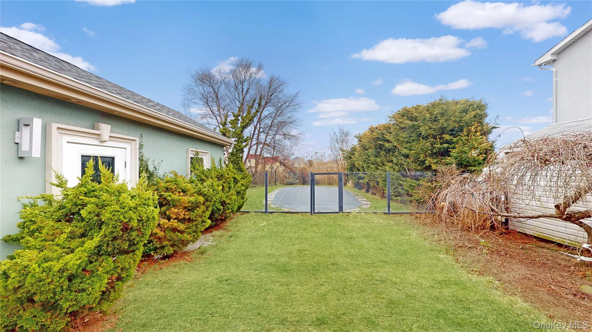 Expansive grassy lawn with manicured shrubbery bordering a light blue stucco exterior Expansive grassy lawn with manicured shrubbery bordering a light blue stucco exterior