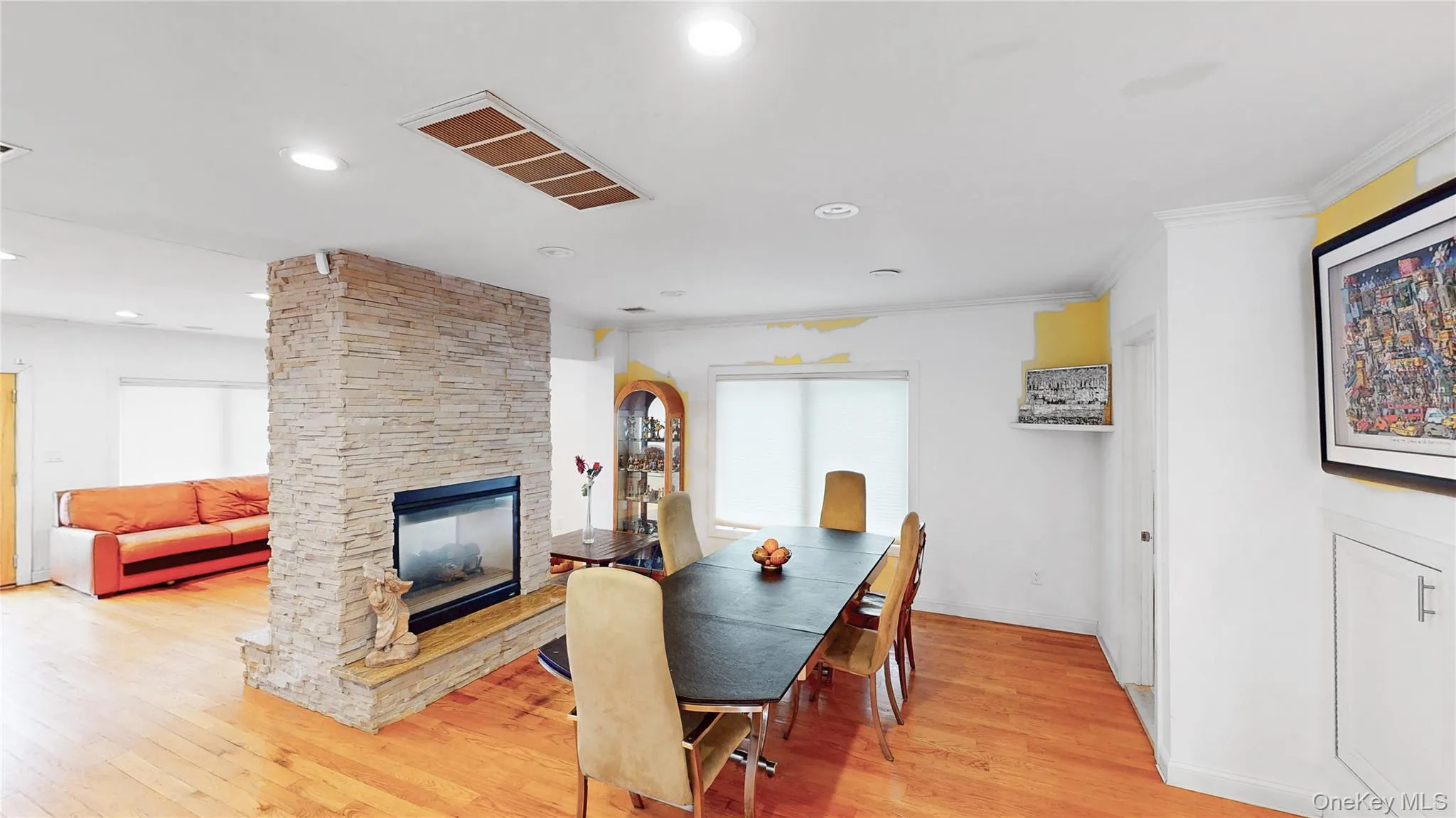 Stone-clad fireplace with a raised hearth separating two distinct areas Stone-clad fireplace with a raised hearth separating two distinct areas