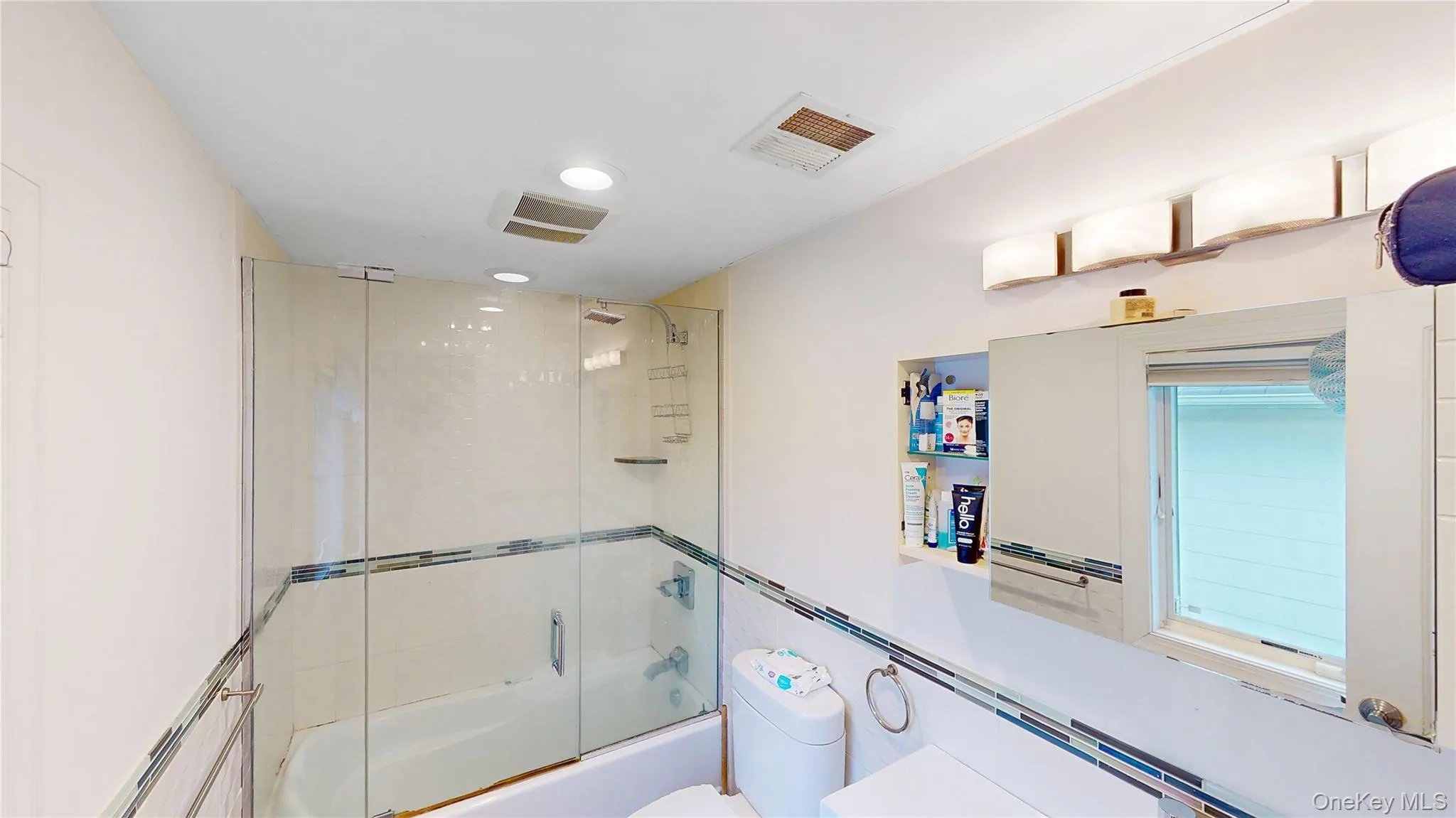 Bathroom featuring a glass-enclosed tub-shower combination, recessed lighting, and a vanity light fixture Bathroom featuring a glass-enclosed tub-shower combination, recessed lighting, and a vanity light fixture