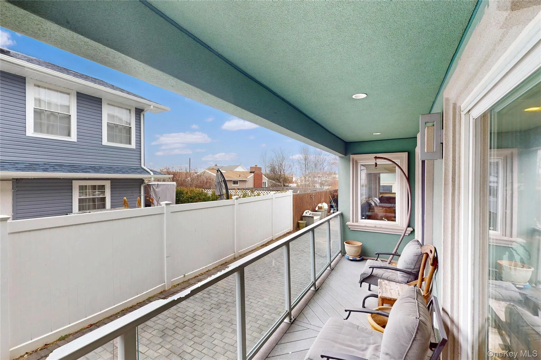 Covered balcony featuring a glass railing, recessed lighting, and a window with trim Covered balcony featuring a glass railing, recessed lighting, and a window with trim