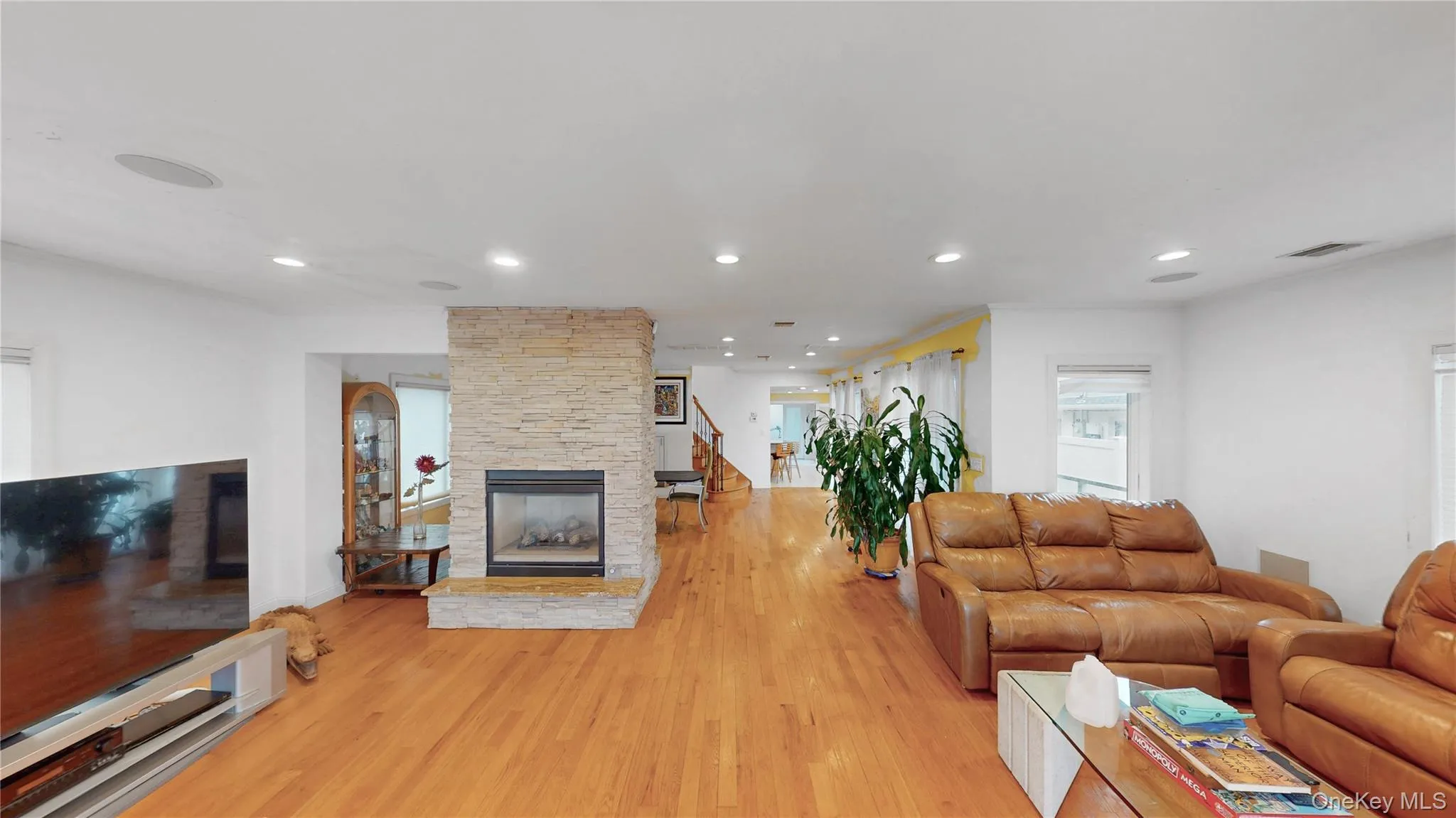Living area featuring wood-finish flooring, a stone-clad fireplace, recessed lighting, and built-in ceiling speakers Living area featuring wood-finish flooring, a stone-clad fireplace, recessed lighting, and built-in ceiling speakers