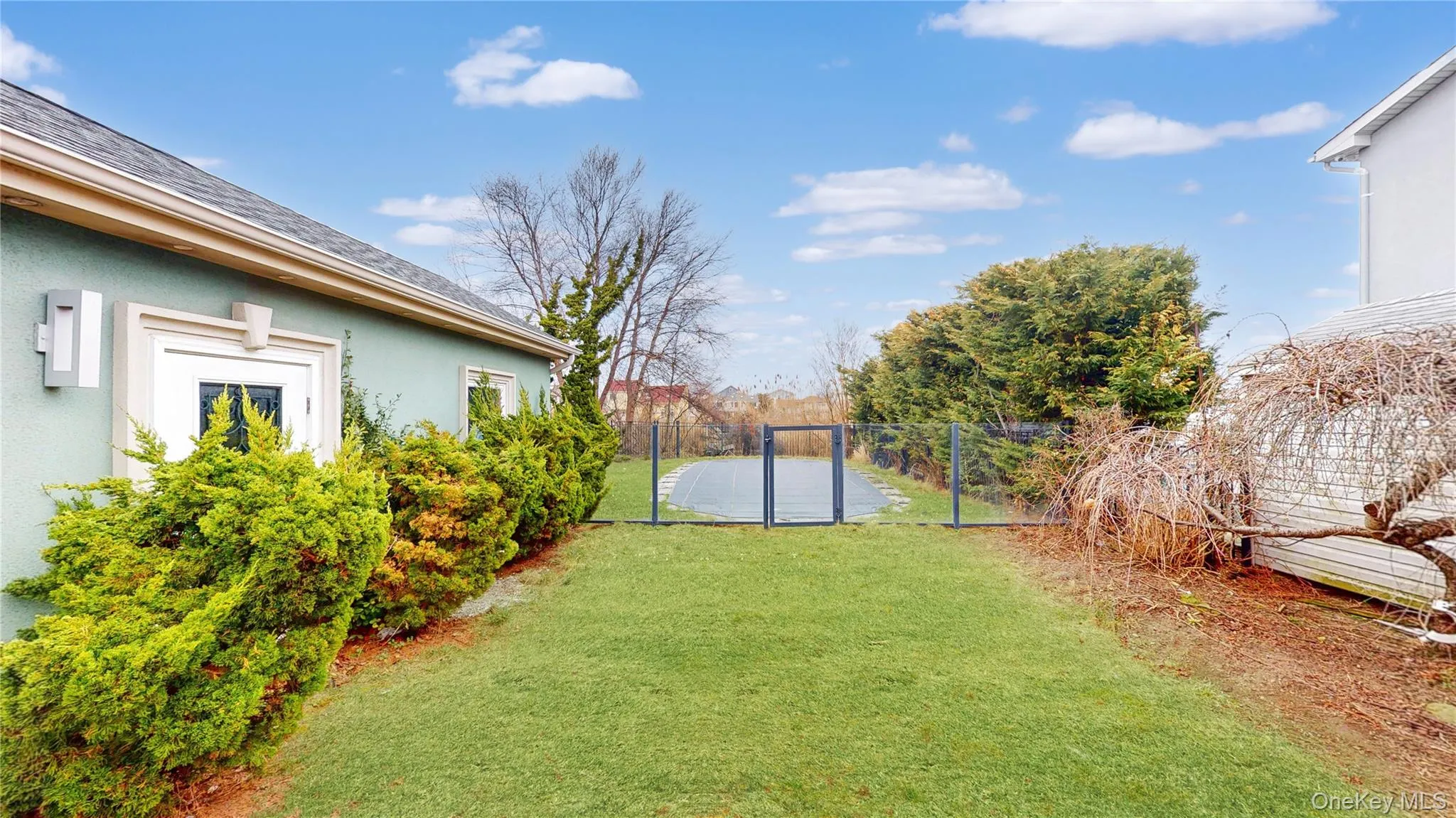 Manicured lawn area with lush shrubbery bordering a light blue stucco exterior Manicured lawn area with lush shrubbery bordering a light blue stucco exterior