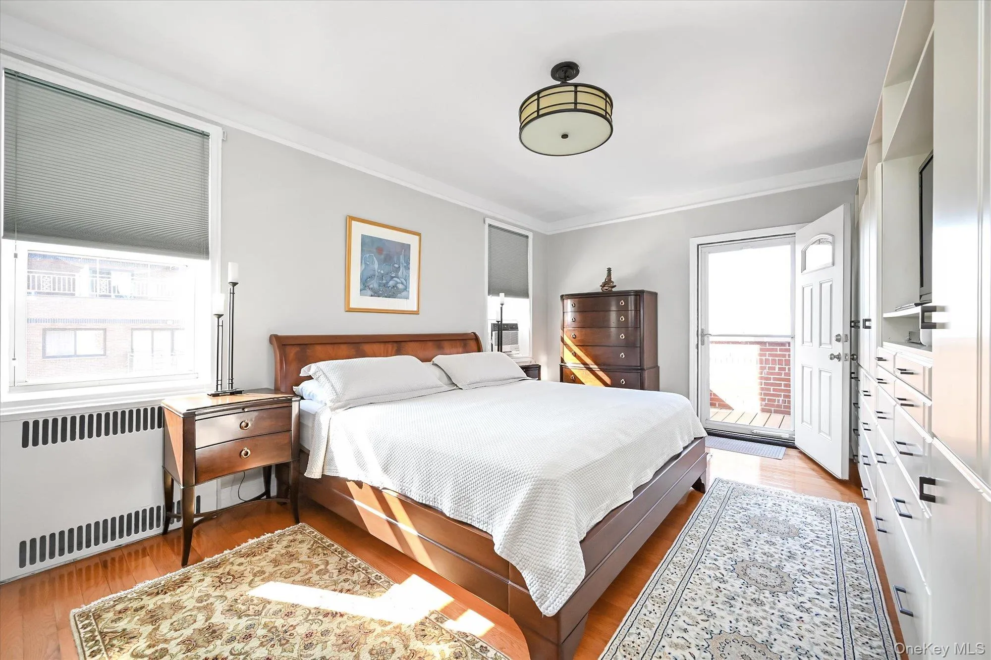 Full view of Primary bedroom with balcony entrance. Beautifully renovated hardwood floors Full view of Primary bedroom with balcony entrance. Beautifully renovated hardwood floors