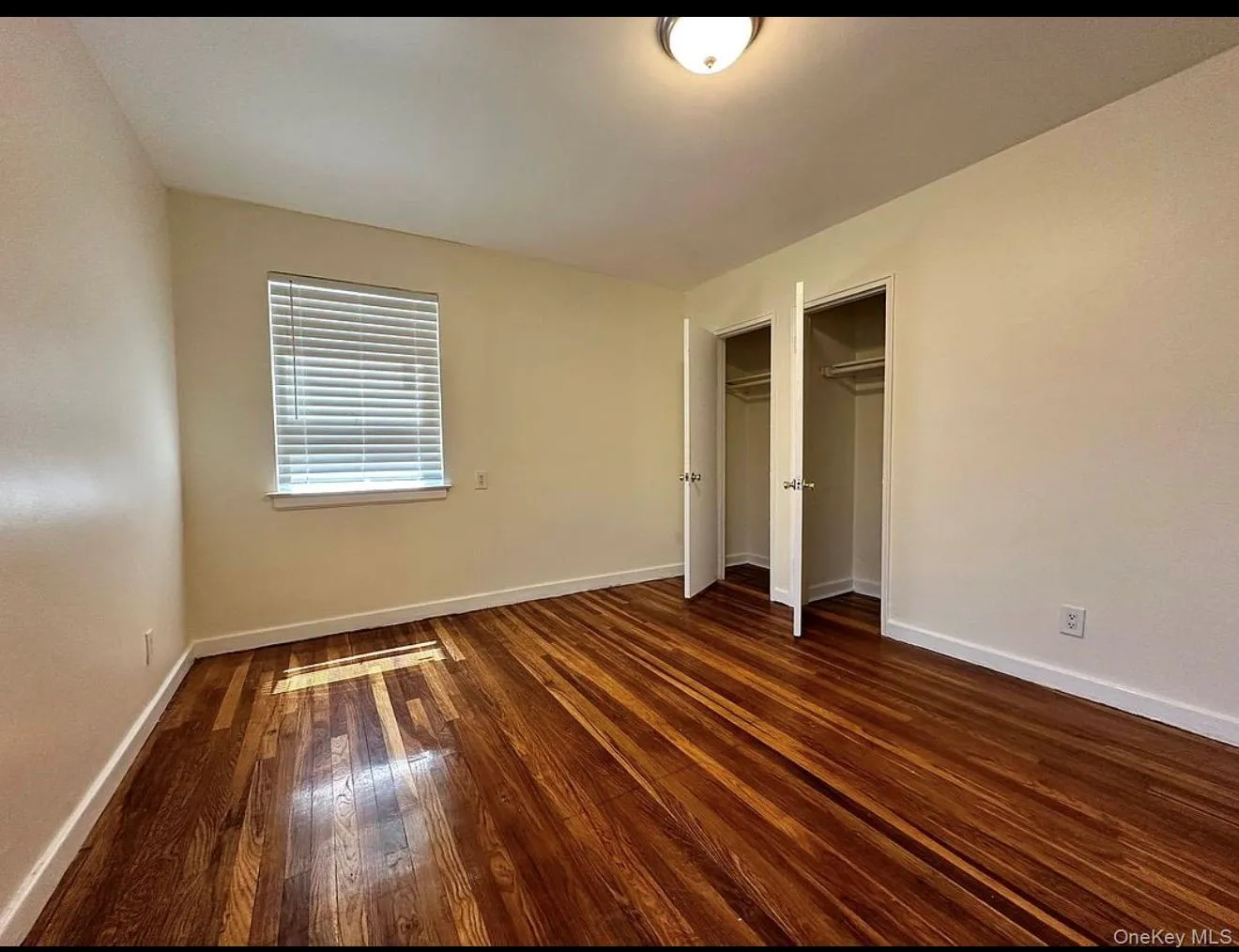Room featuring wood-finish flooring, neutral wall tones, and white trim Room featuring wood-finish flooring, neutral wall tones, and white trim