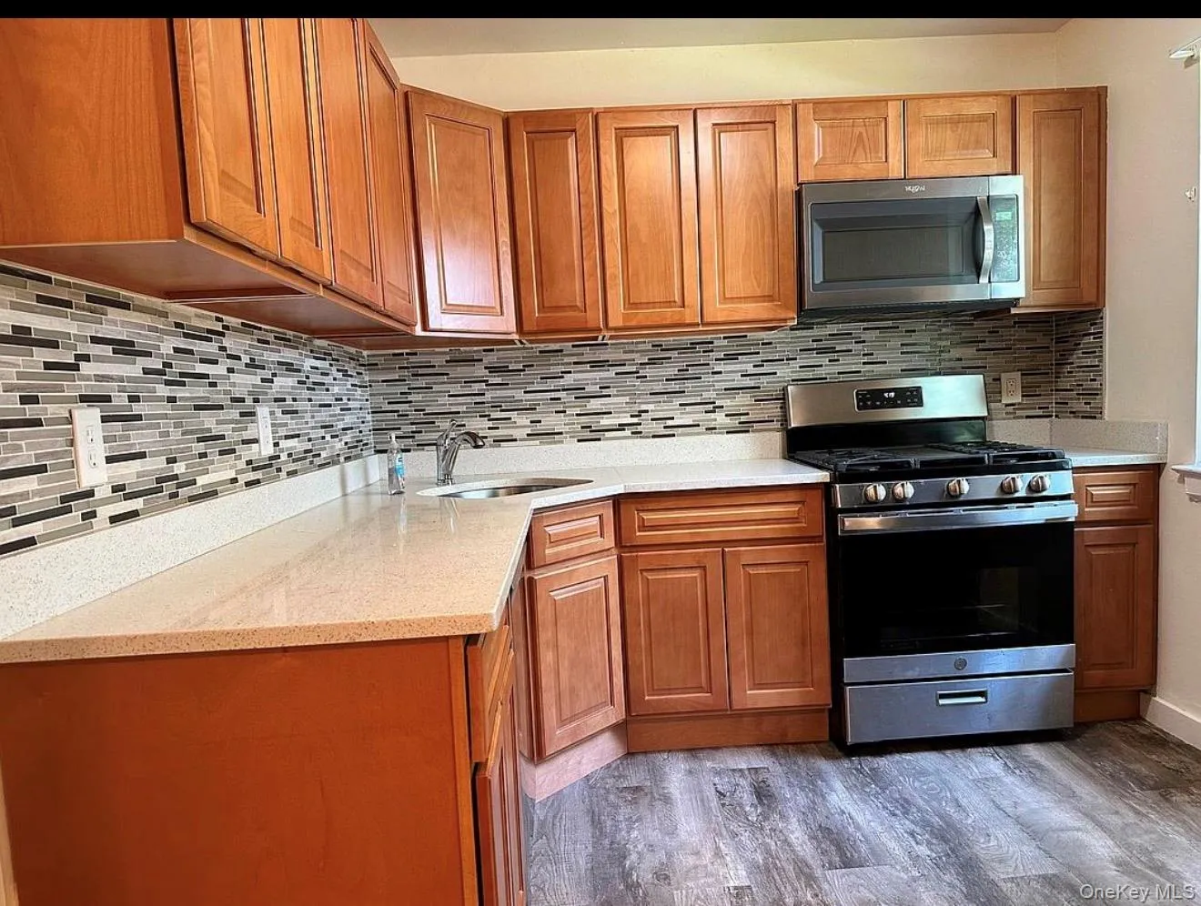 Kitchen featuring light wood cabinetry, light-toned countertops, and a full tile backsplash Kitchen featuring light wood cabinetry, light-toned countertops, and a full tile backsplash