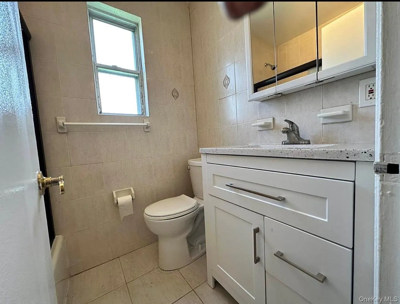 Bathroom featuring a white vanity with brushed nickel hardware, a white countertop, and a white toilet Bathroom featuring a white vanity with brushed nickel hardware, a white countertop, and a white toilet