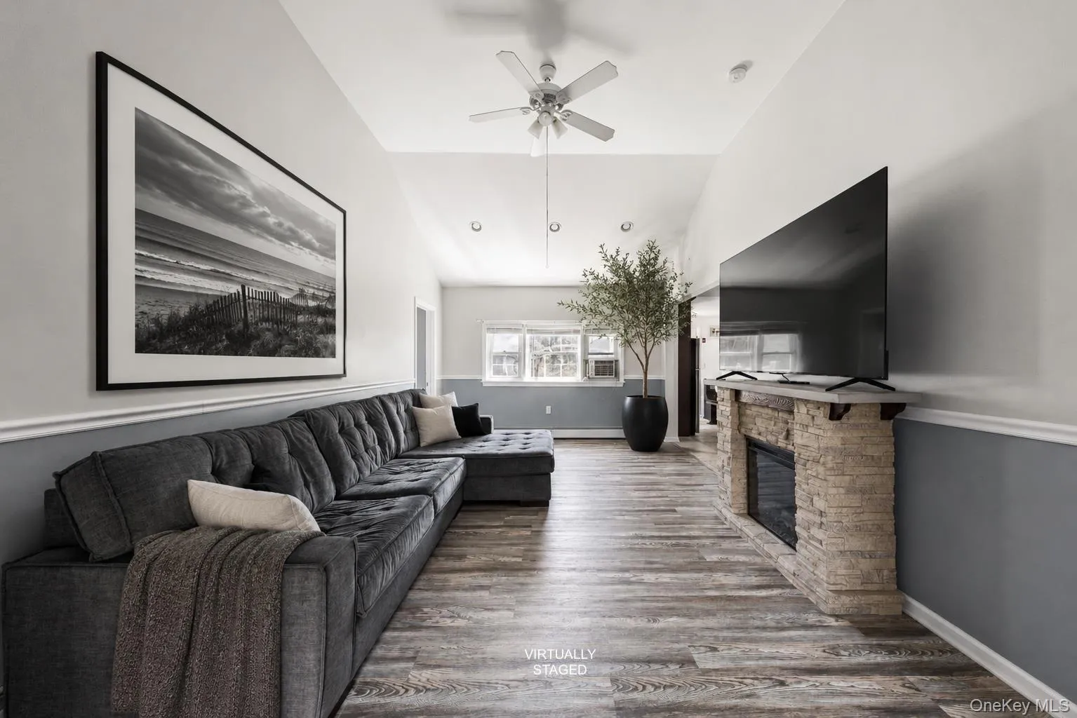 Spacious living area featuring high ceilings, wood looking-finish flooring, a stone-clad removable fireplace with mantel, and recessed lighting Spacious living area featuring high ceilings, wood looking-finish flooring, a stone-clad removable fireplace with mantel, and recessed lighting