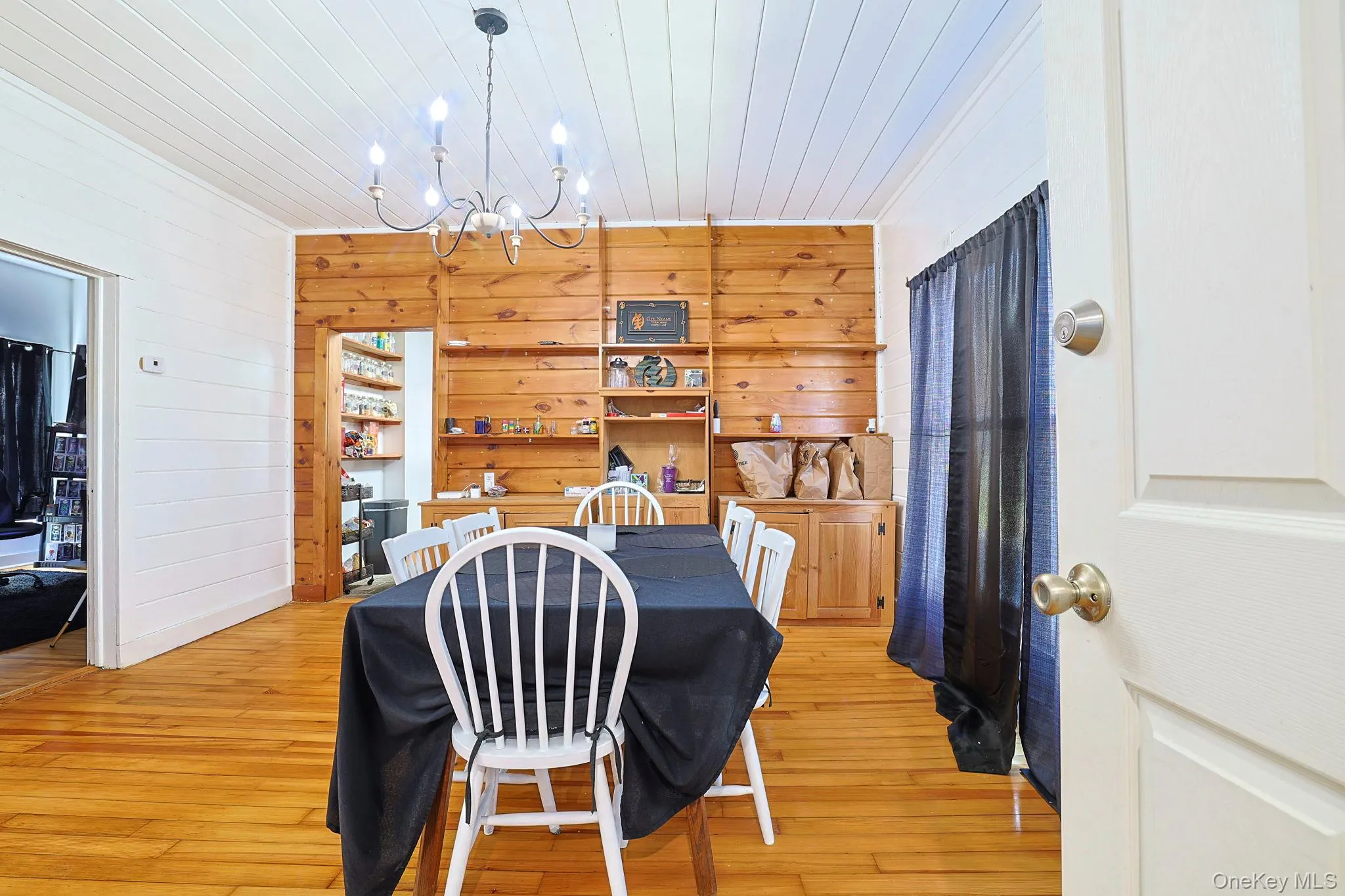 Dining area featuring light wood-type flooring, wood walls, wood ceiling, and a notable chandelier Dining area featuring light wood-type flooring, wood walls, wood ceiling, and a notable chandelier