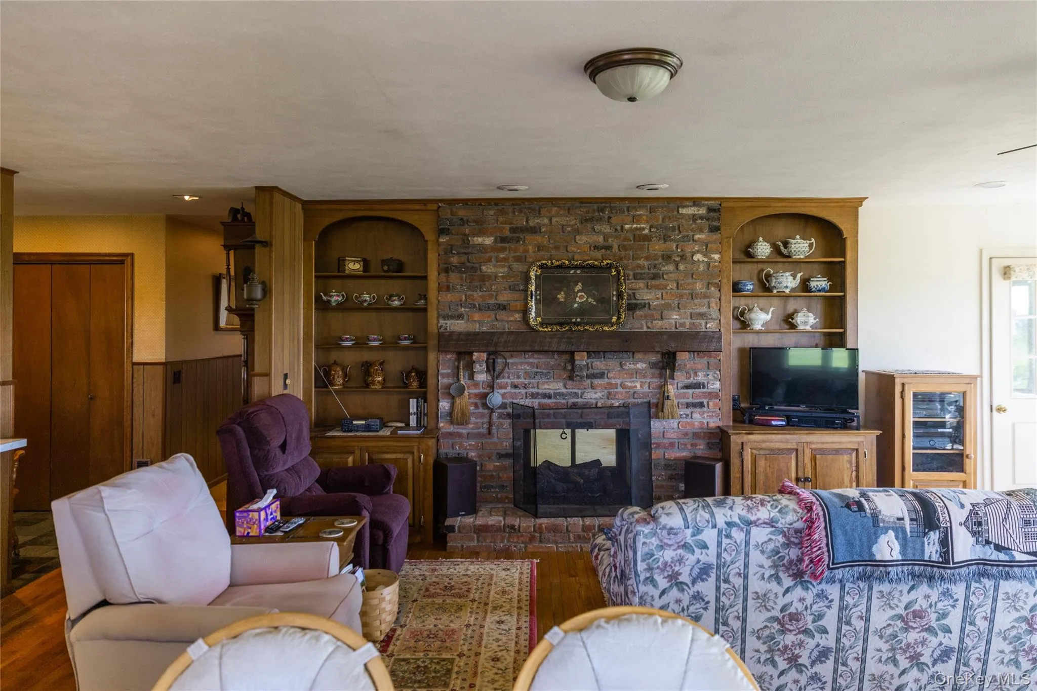 Brick fireplace with a substantial wood mantel, flanked by built-in wood shelving units with arched tops Brick fireplace with a substantial wood mantel, flanked by built-in wood shelving units with arched tops