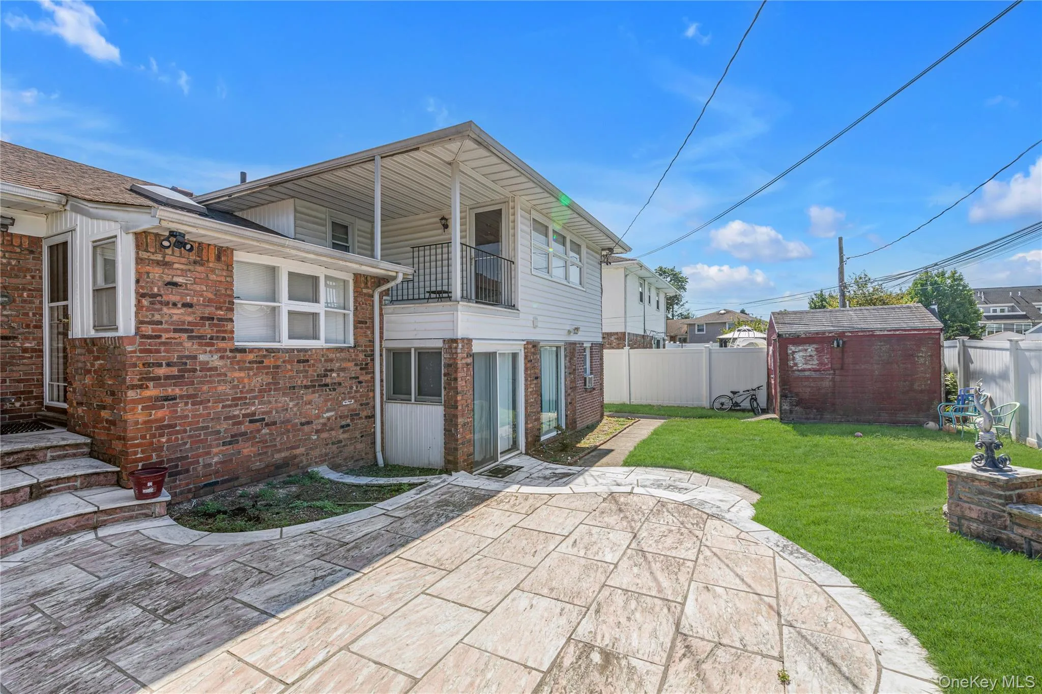 Rear view of house with a shed, a fenced backyard, a balcony, brick siding, and a patio Rear view of house with a shed, a fenced backyard, a balcony, brick siding, and a patio