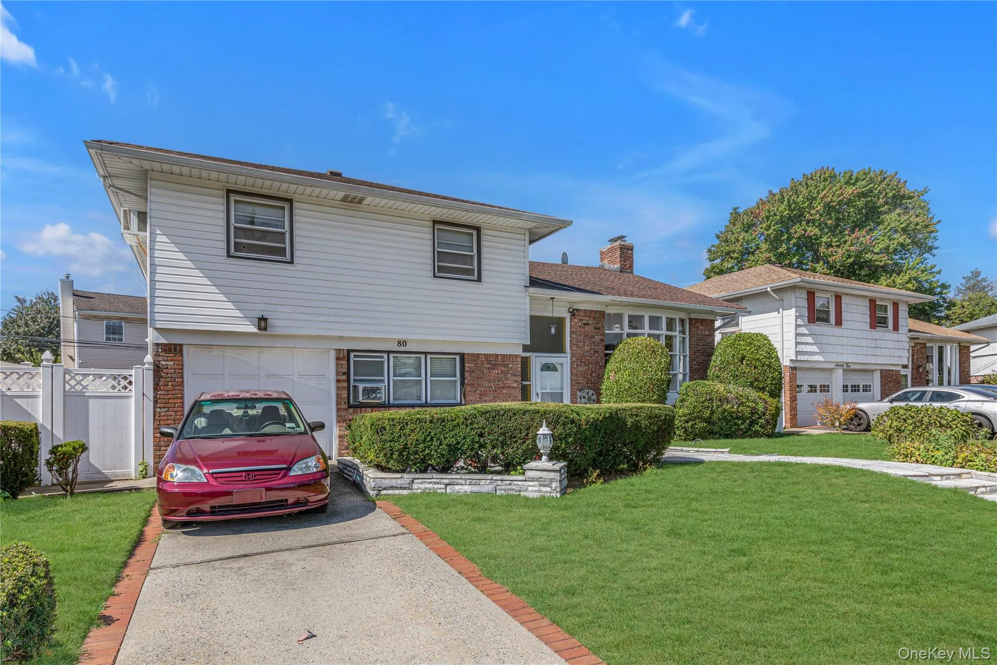 Split level home with brick siding, driveway, and a chimney Split level home with brick siding, driveway, and a chimney