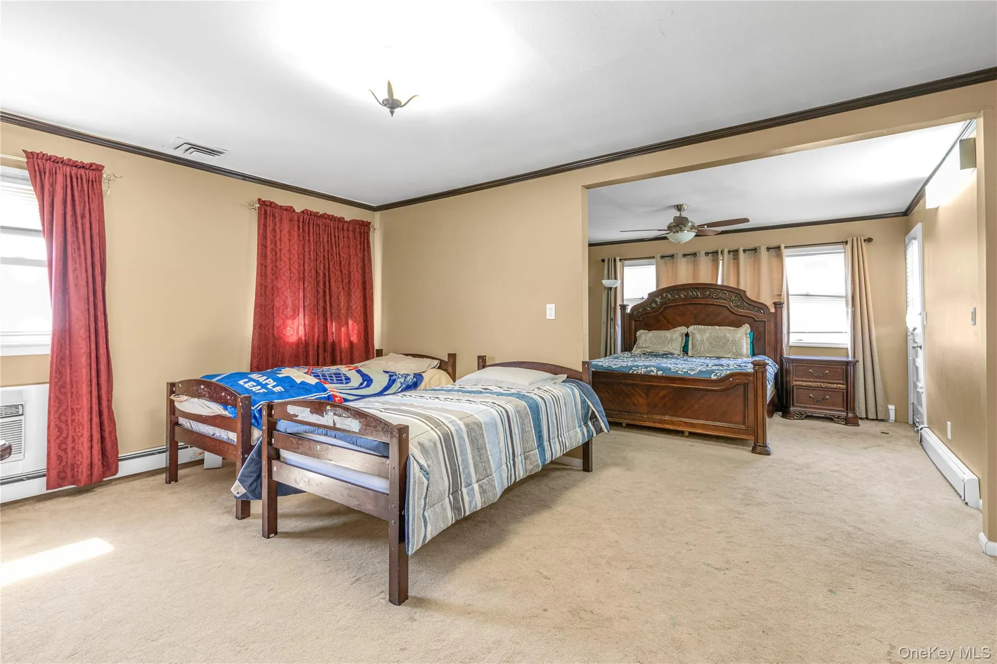 Bedroom with crown molding, light colored carpet, and a baseboard radiator Bedroom with crown molding, light colored carpet, and a baseboard radiator