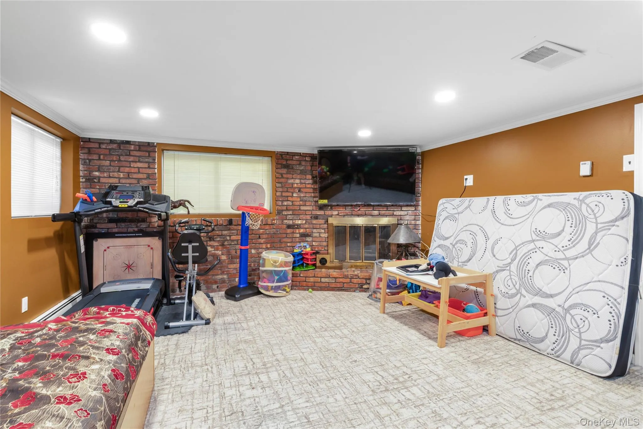 Playroom featuring crown molding, a baseboard radiator, brick wall, and recessed lighting Playroom featuring crown molding, a baseboard radiator, brick wall, and recessed lighting