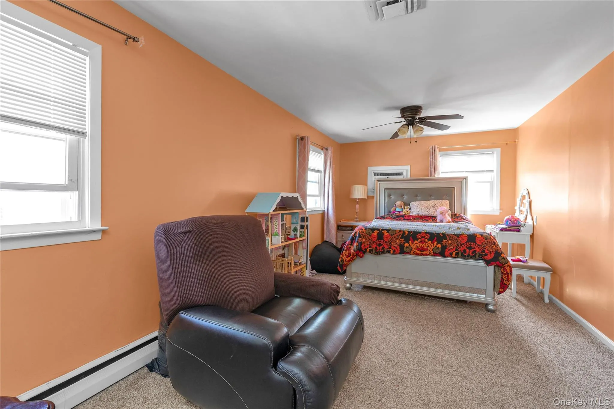 Carpeted bedroom with a baseboard radiator, multiple windows, and ceiling fan Carpeted bedroom with a baseboard radiator, multiple windows, and ceiling fan