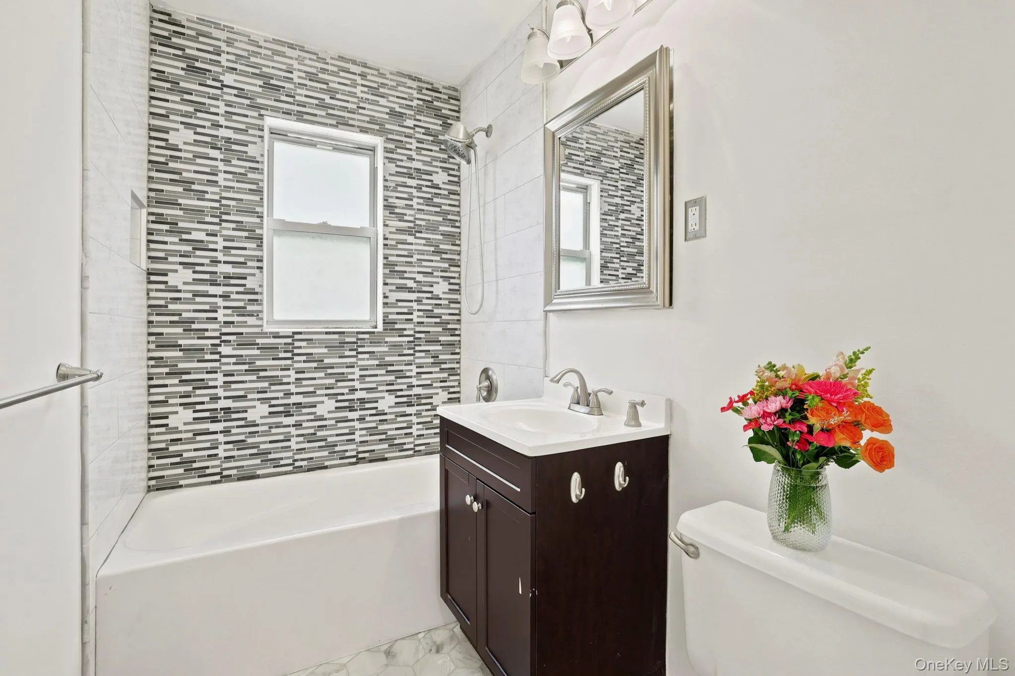 The renovated bathroom has a new ceramic tile floor and cultured marble-top vanity and a wall of contemporary tile in the bathtub area. The renovated bathroom has a new ceramic tile floor and cultured marble-top vanity and a wall of contemporary tile in the bathtub area.