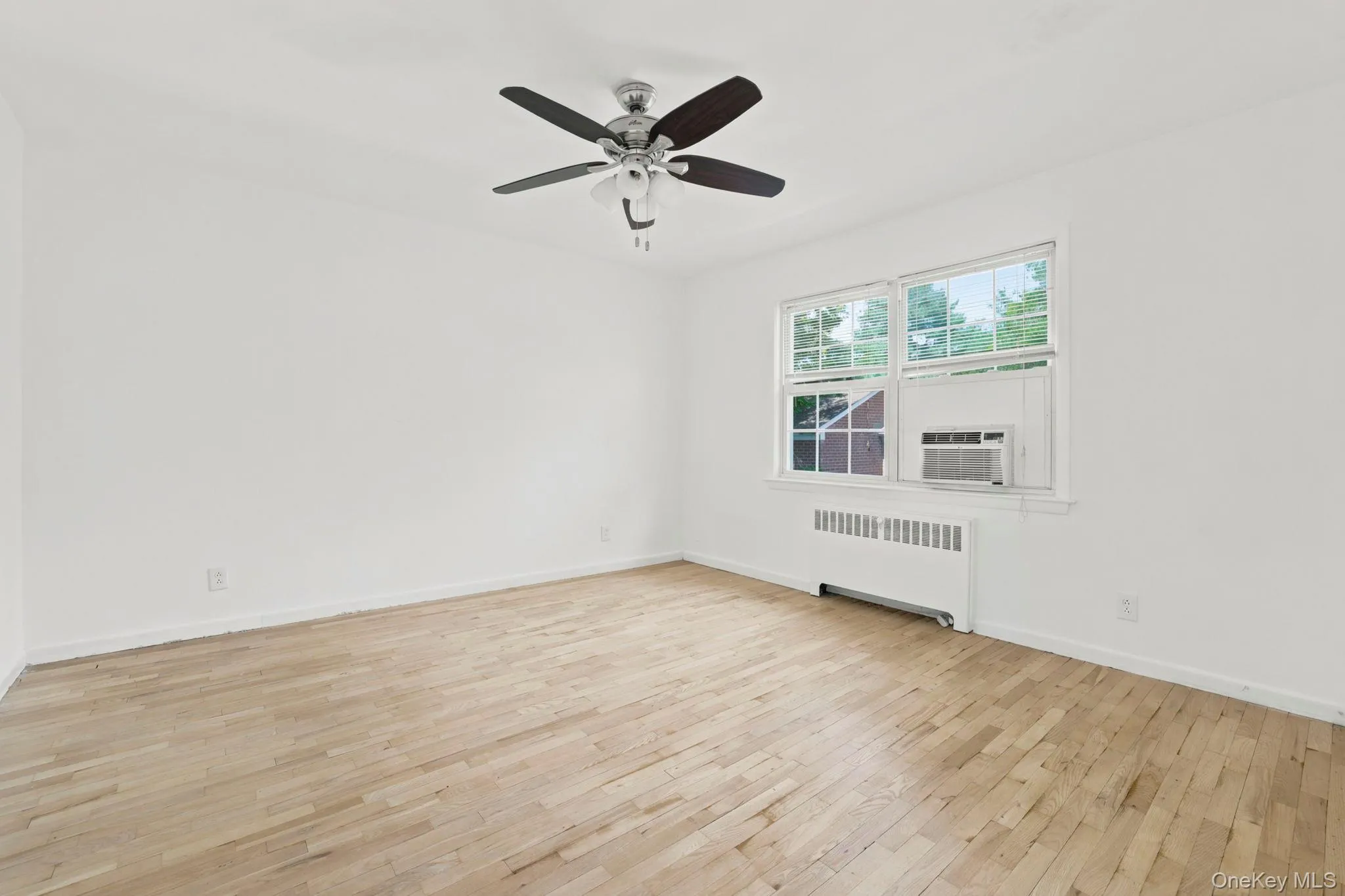 The bedroom has wood floors, a lighted ceiling fan, and wooded and courtyard views from the windows The bedroom has wood floors, a lighted ceiling fan, and wooded and courtyard views from the windows