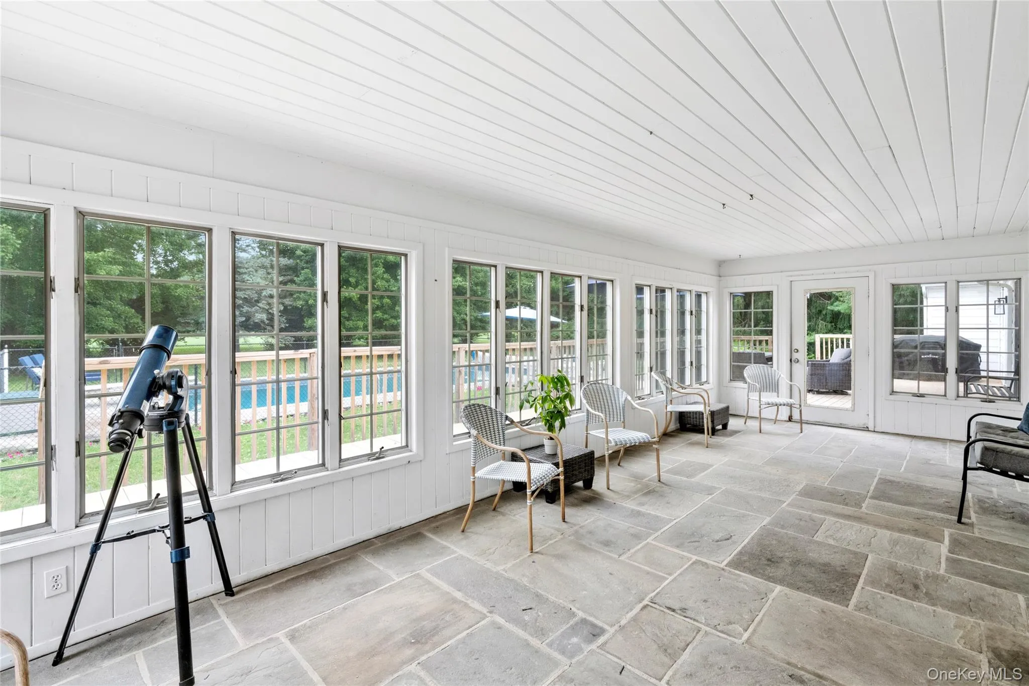 A sun filled enclosed porch offering beautiful views of the surrounding landscape. A sun filled enclosed porch offering beautiful views of the surrounding landscape.