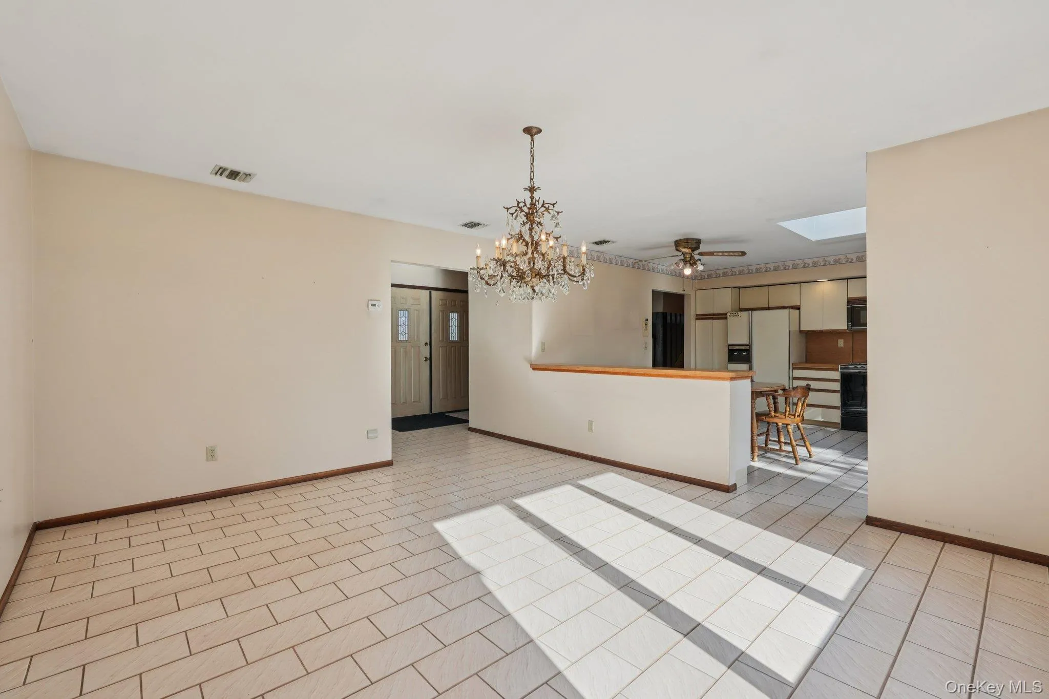 Spare room featuring a ceiling fan, a chandelier, a skylight, and light tile patterned floors Spare room featuring a ceiling fan, a chandelier, a skylight, and light tile patterned floors