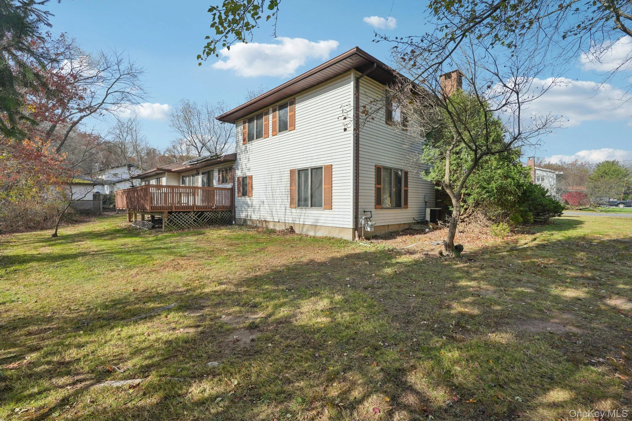 Rear view of property featuring a lawn, a wooden deck, and a chimney Rear view of property featuring a lawn, a wooden deck, and a chimney