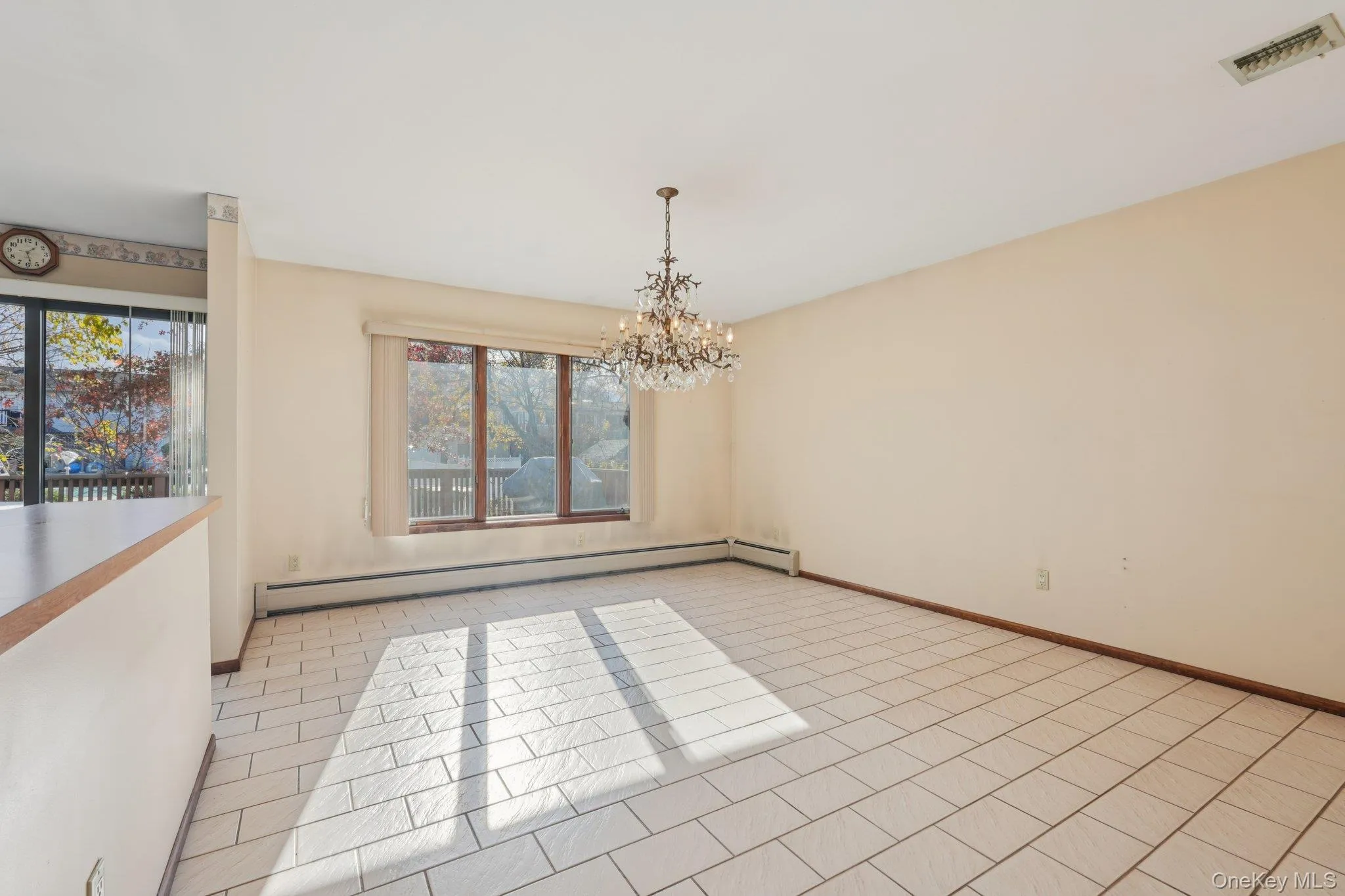 Spare room featuring baseboard heating, a chandelier, and light tile patterned flooring Spare room featuring baseboard heating, a chandelier, and light tile patterned flooring