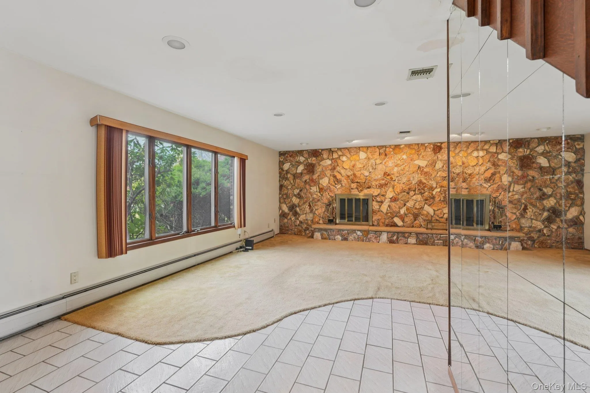 Unfurnished living room featuring carpet floors, a fireplace, and a baseboard heating unit Unfurnished living room featuring carpet floors, a fireplace, and a baseboard heating unit