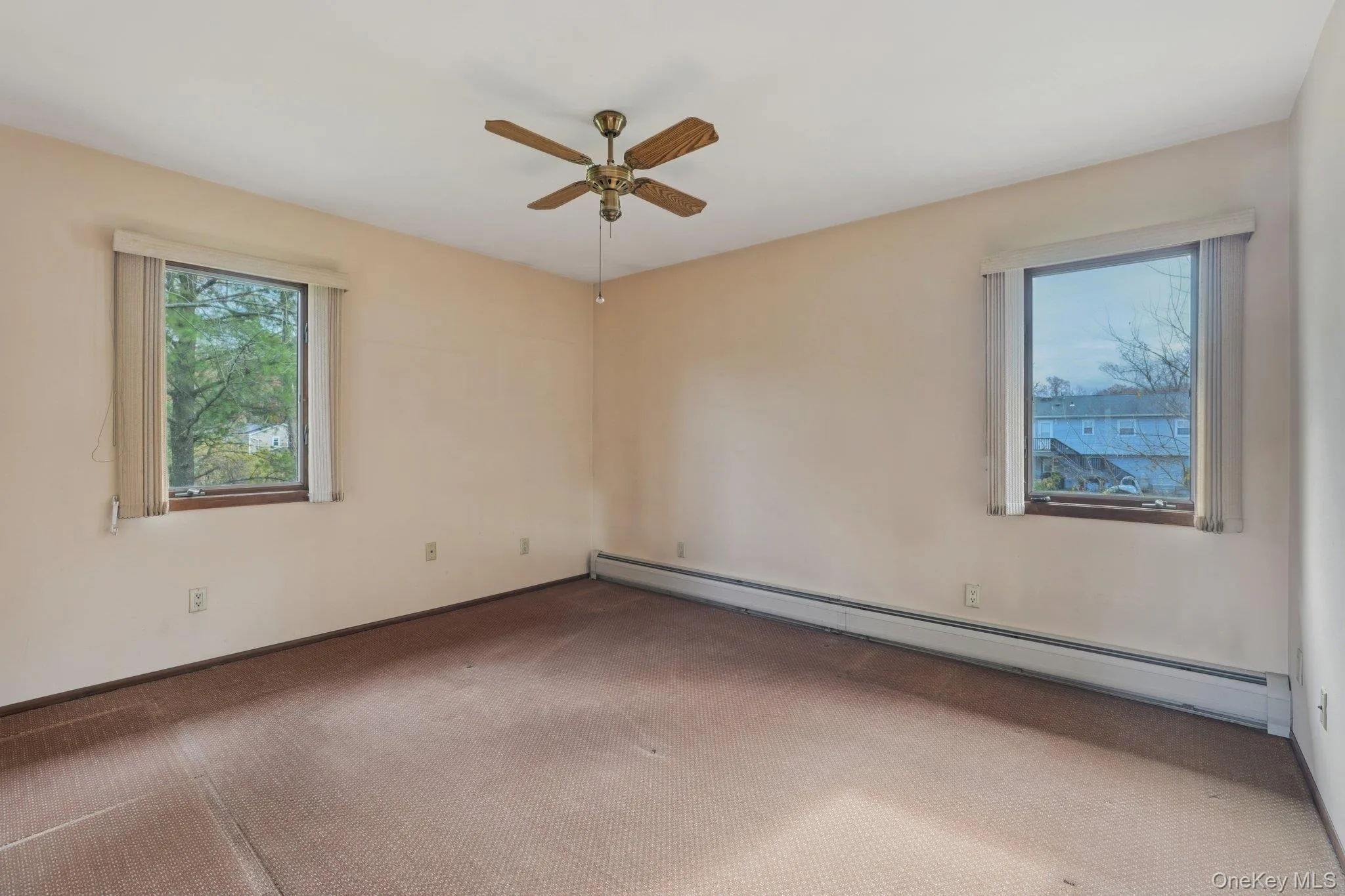 Carpeted empty room with baseboard heating and a ceiling fan Carpeted empty room with baseboard heating and a ceiling fan