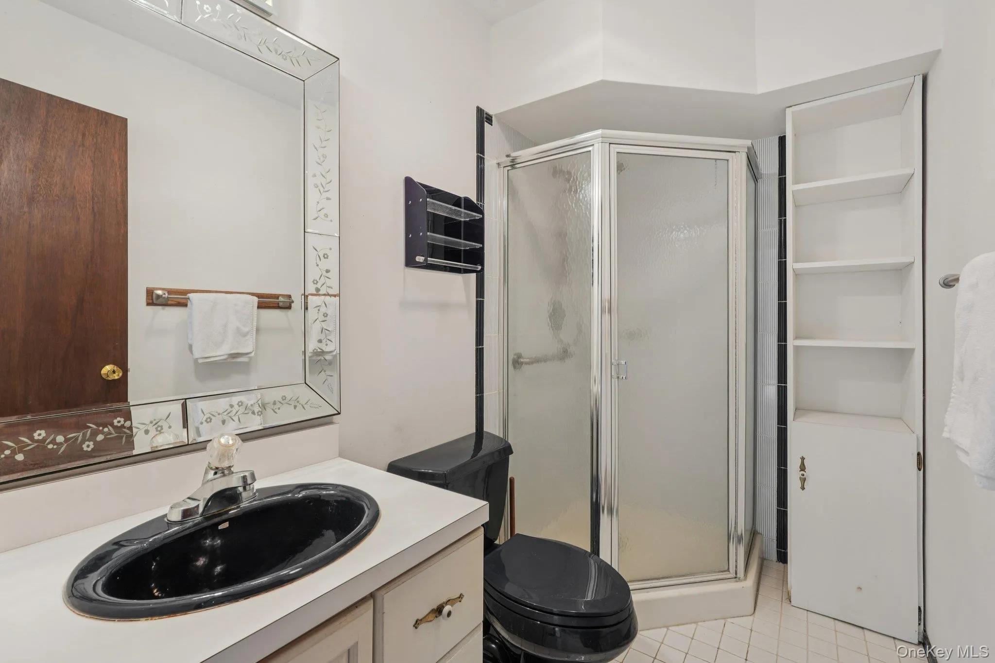 Full bath featuring a stall shower, vanity, and light tile patterned floors Full bath featuring a stall shower, vanity, and light tile patterned floors