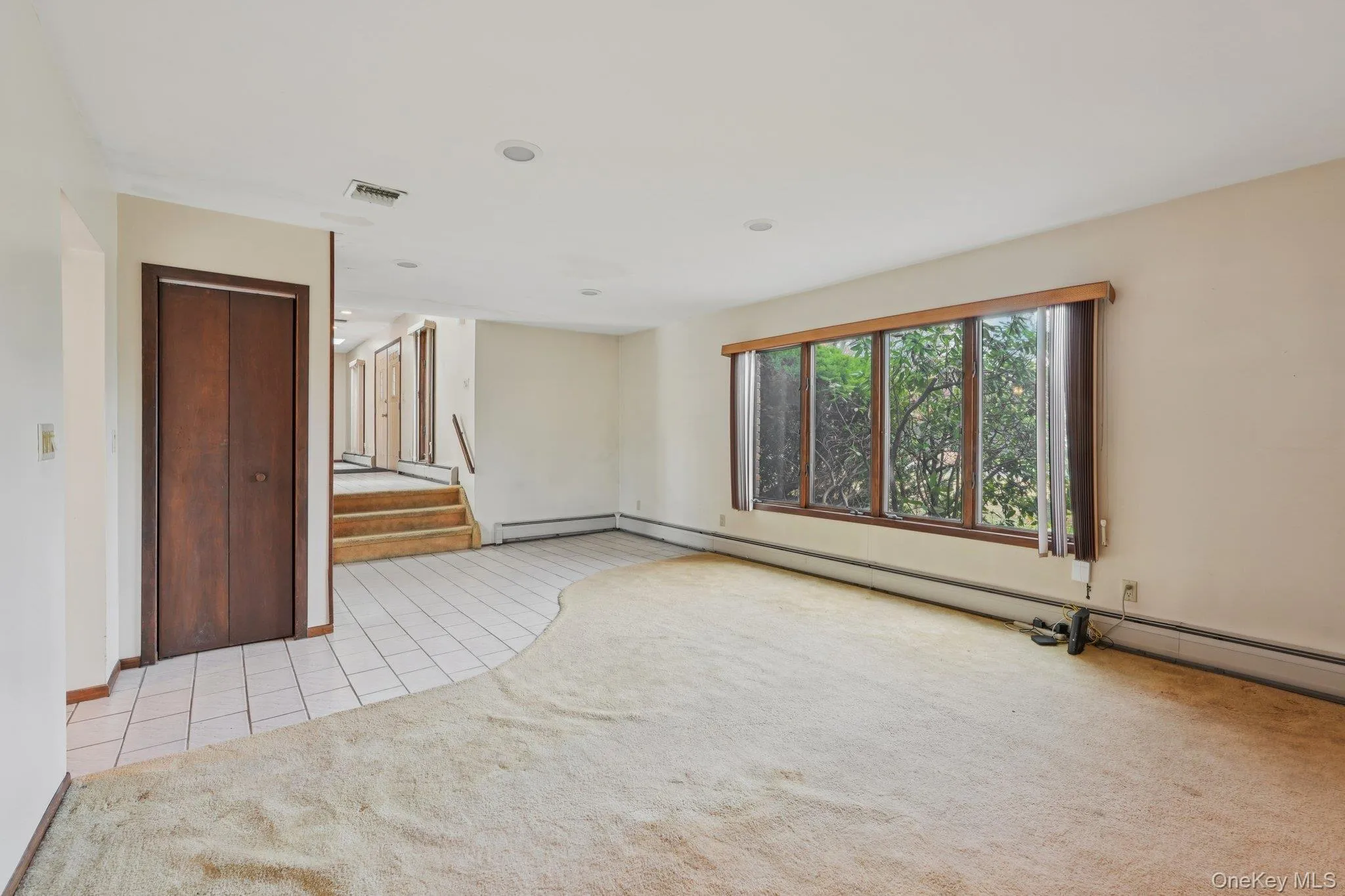 Spare room with light tile patterned floors, light colored carpet, a baseboard heating unit, stairs, and recessed lighting Spare room with light tile patterned floors, light colored carpet, a baseboard heating unit, stairs, and recessed lighting