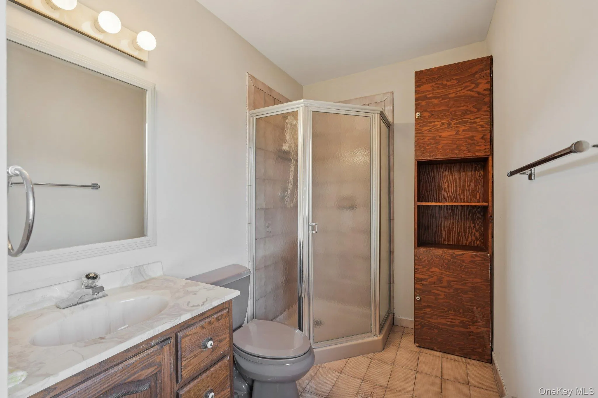 Full bath featuring light tile patterned flooring, vanity, and a stall shower Full bath featuring light tile patterned flooring, vanity, and a stall shower