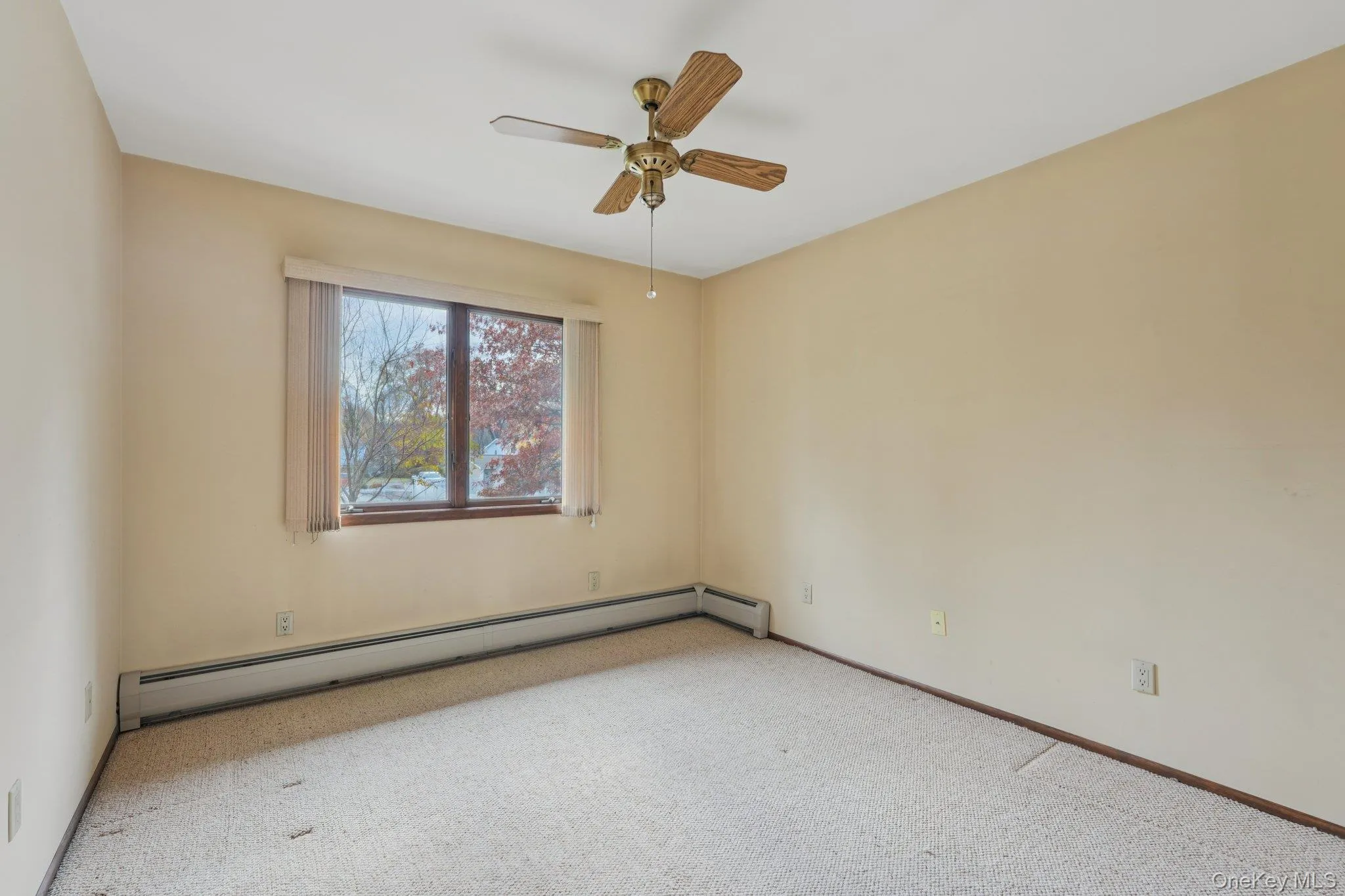 Carpeted spare room featuring a baseboard radiator and ceiling fan Carpeted spare room featuring a baseboard radiator and ceiling fan