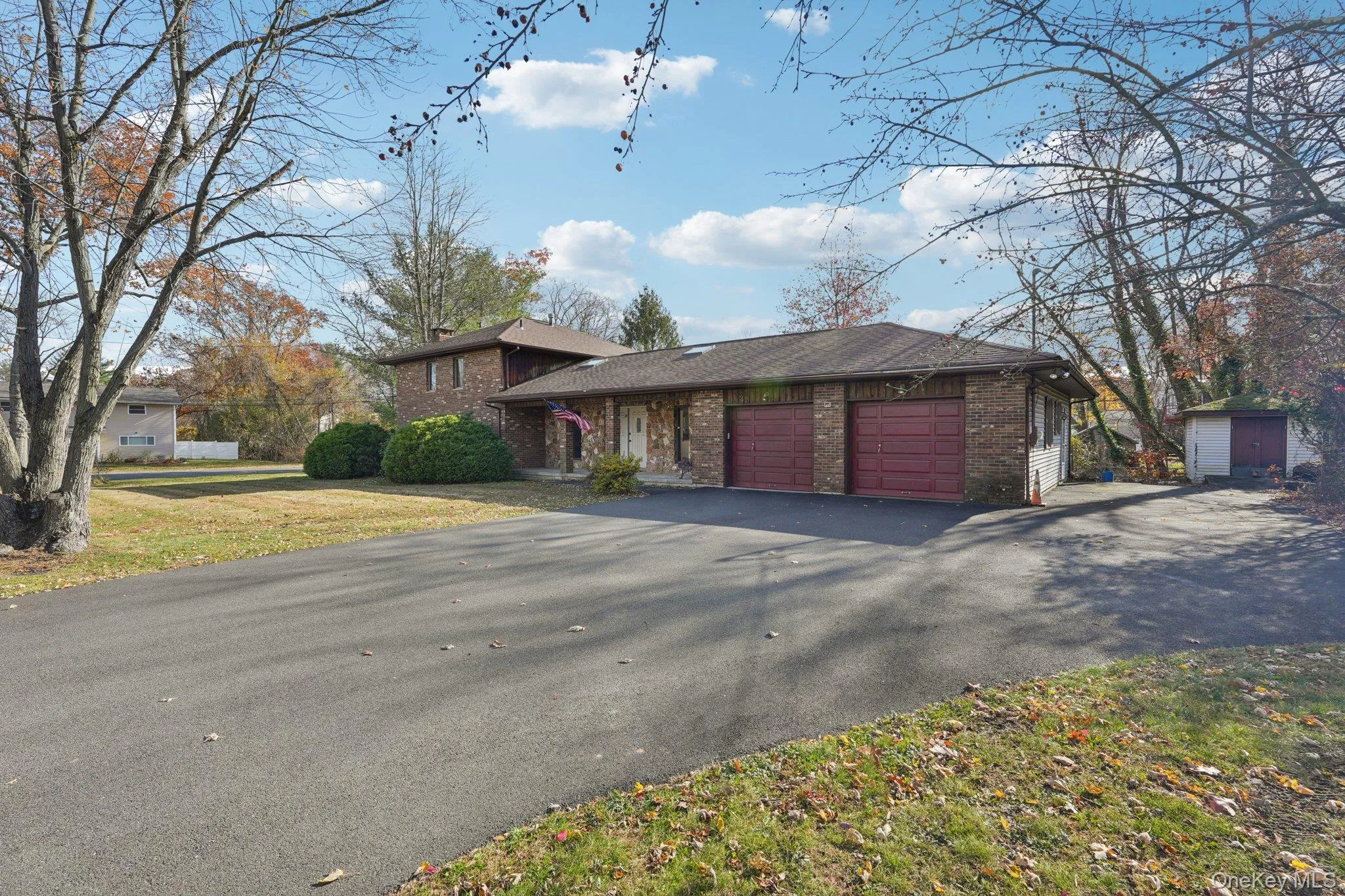 Split level home featuring brick siding, a garage, driveway, and a front yard Split level home featuring brick siding, a garage, driveway, and a front yard