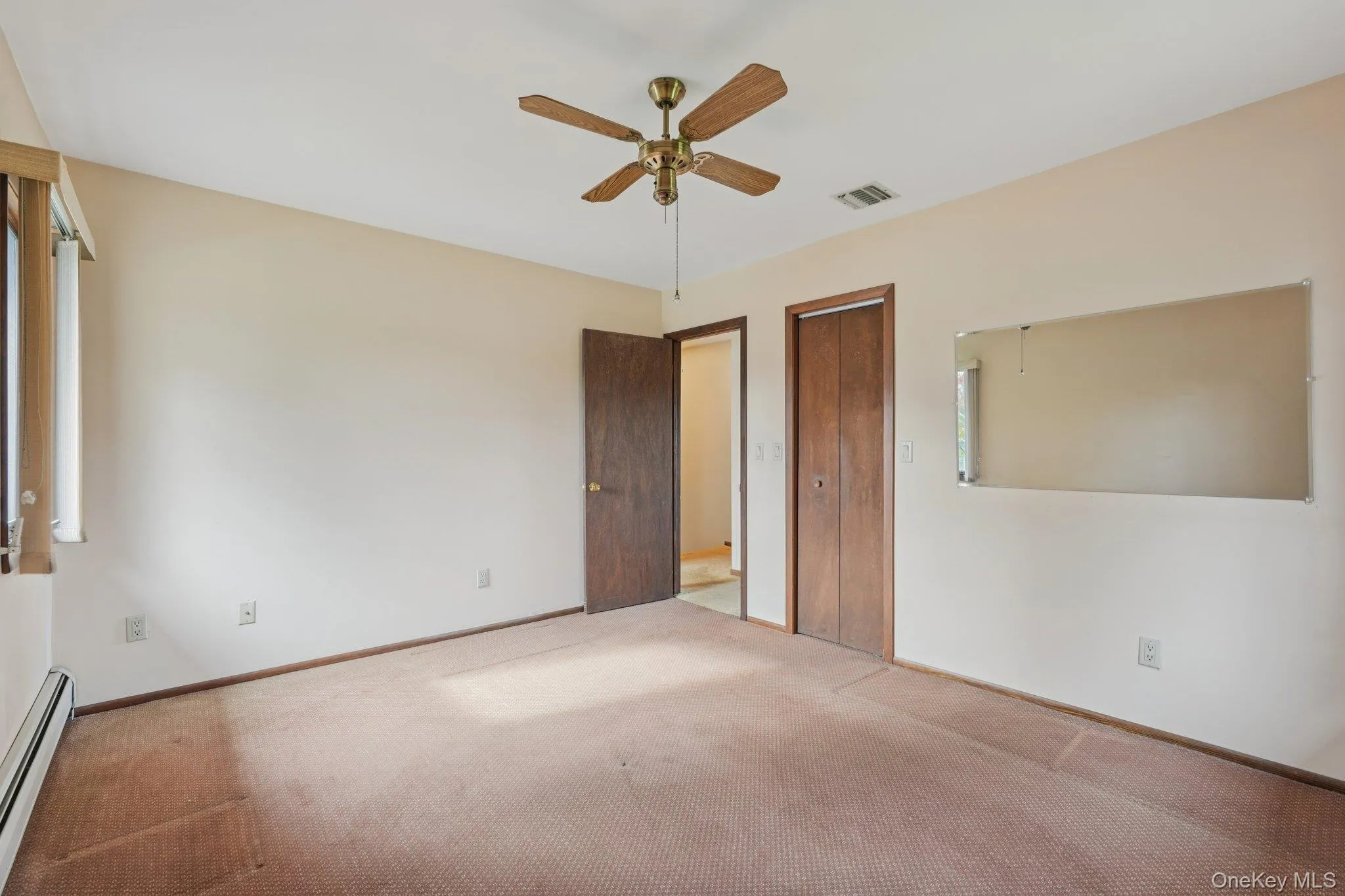 Unfurnished bedroom featuring carpet floors, a baseboard radiator, a closet, and a ceiling fan Unfurnished bedroom featuring carpet floors, a baseboard radiator, a closet, and a ceiling fan