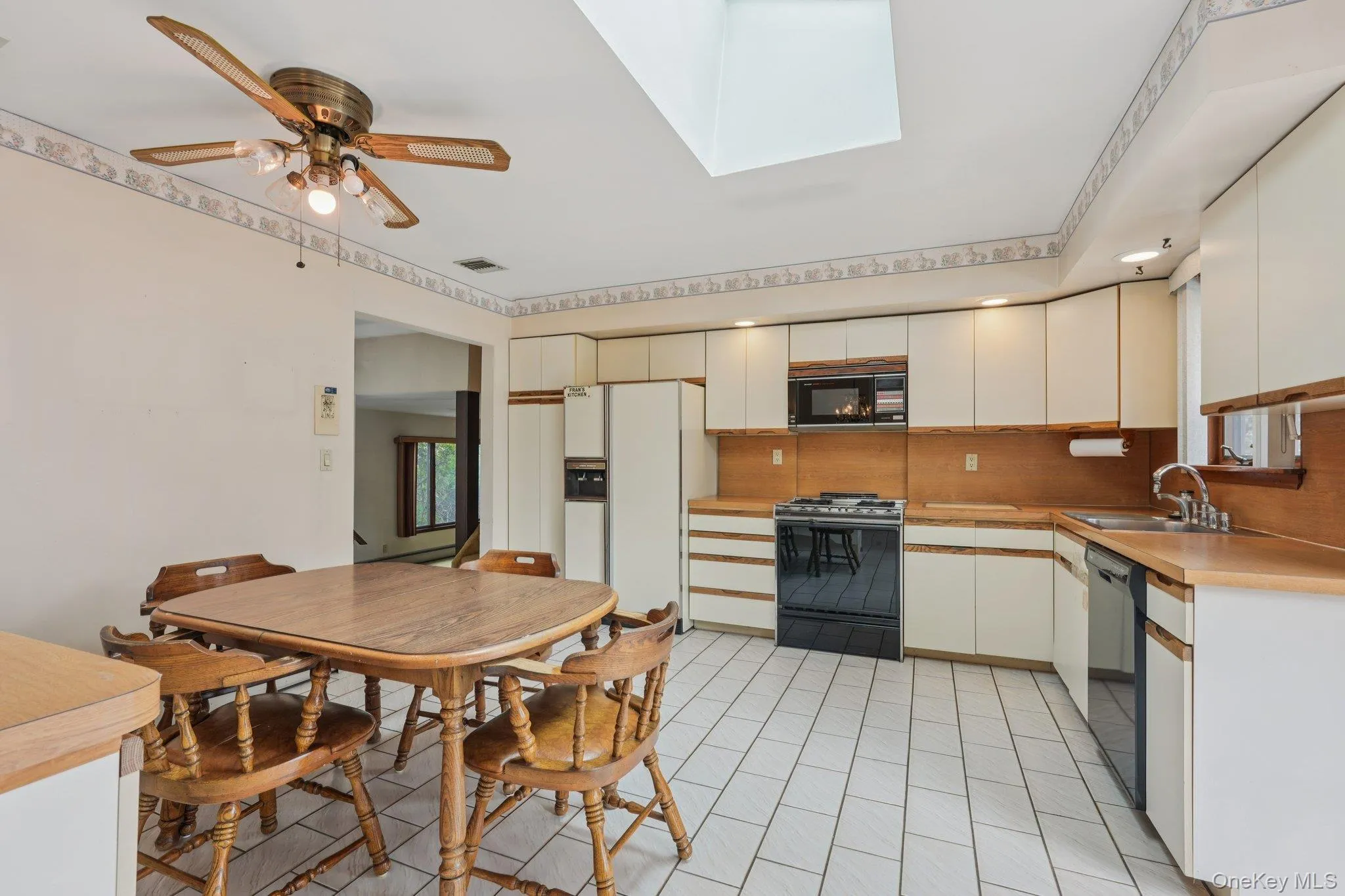 Kitchen featuring black appliances, light countertops, a skylight, backsplash, and ceiling fan Kitchen featuring black appliances, light countertops, a skylight, backsplash, and ceiling fan