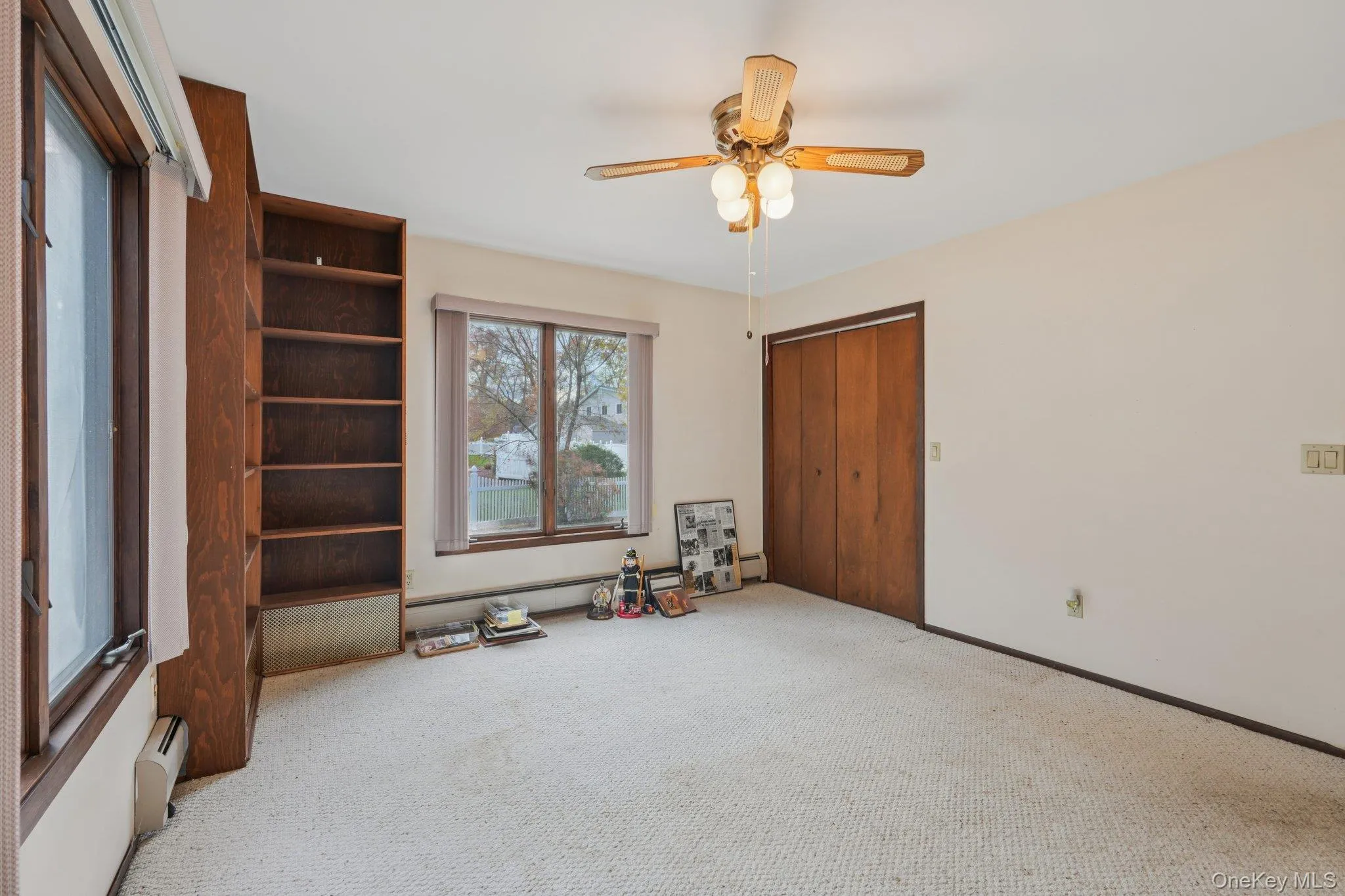 Unfurnished bedroom with carpet flooring, ceiling fan, and a baseboard heating unit Unfurnished bedroom with carpet flooring, ceiling fan, and a baseboard heating unit